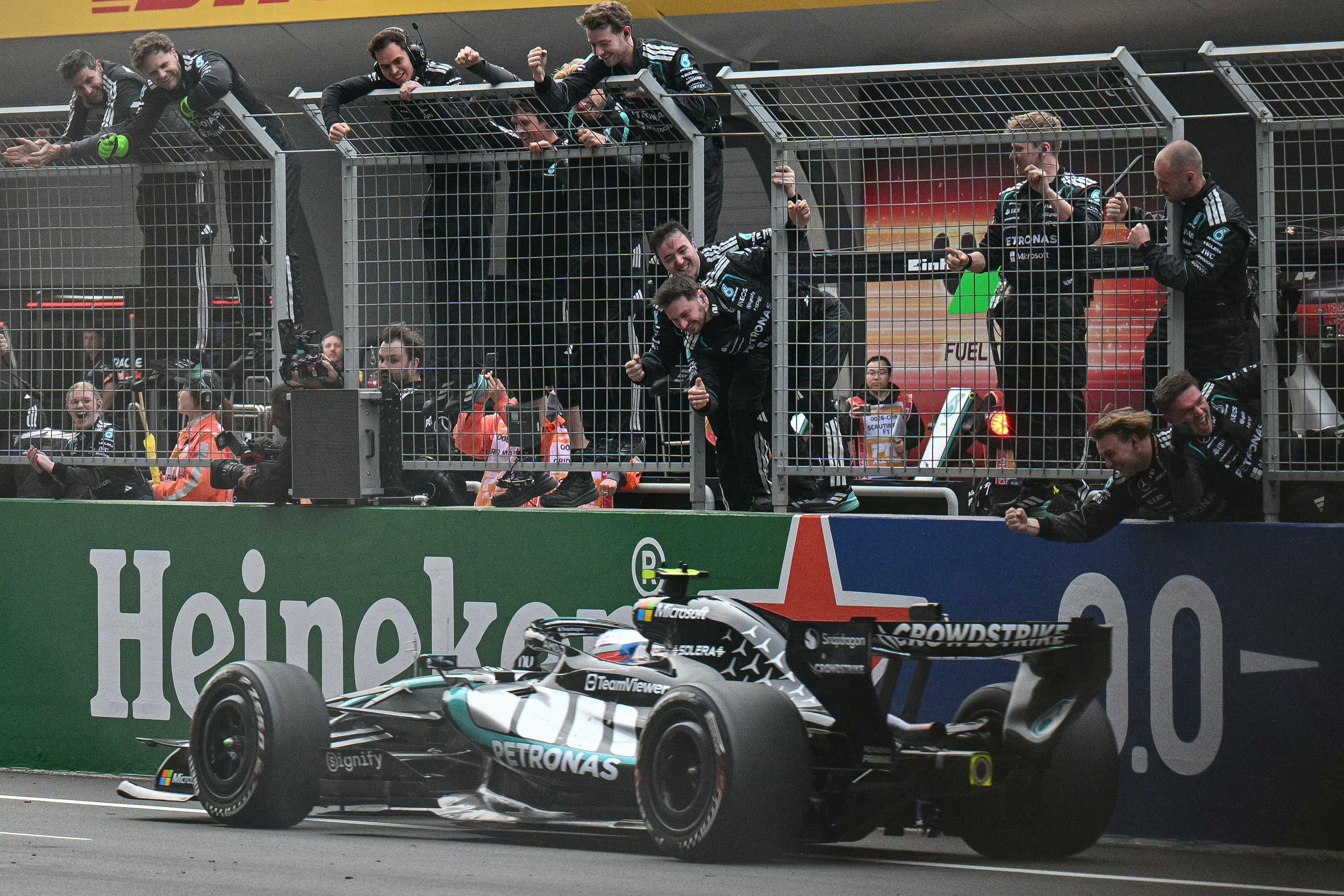 Mercedes' team members celebrate as Mercedes' Italian driver Kimi Antonelli crosses the finish line to win the Formula One Chinese Grand Prix at the Shanghai International Circuit in Shanghai on March 15, 2026. (Photo by HECTOR RETAMAL / AFP)
