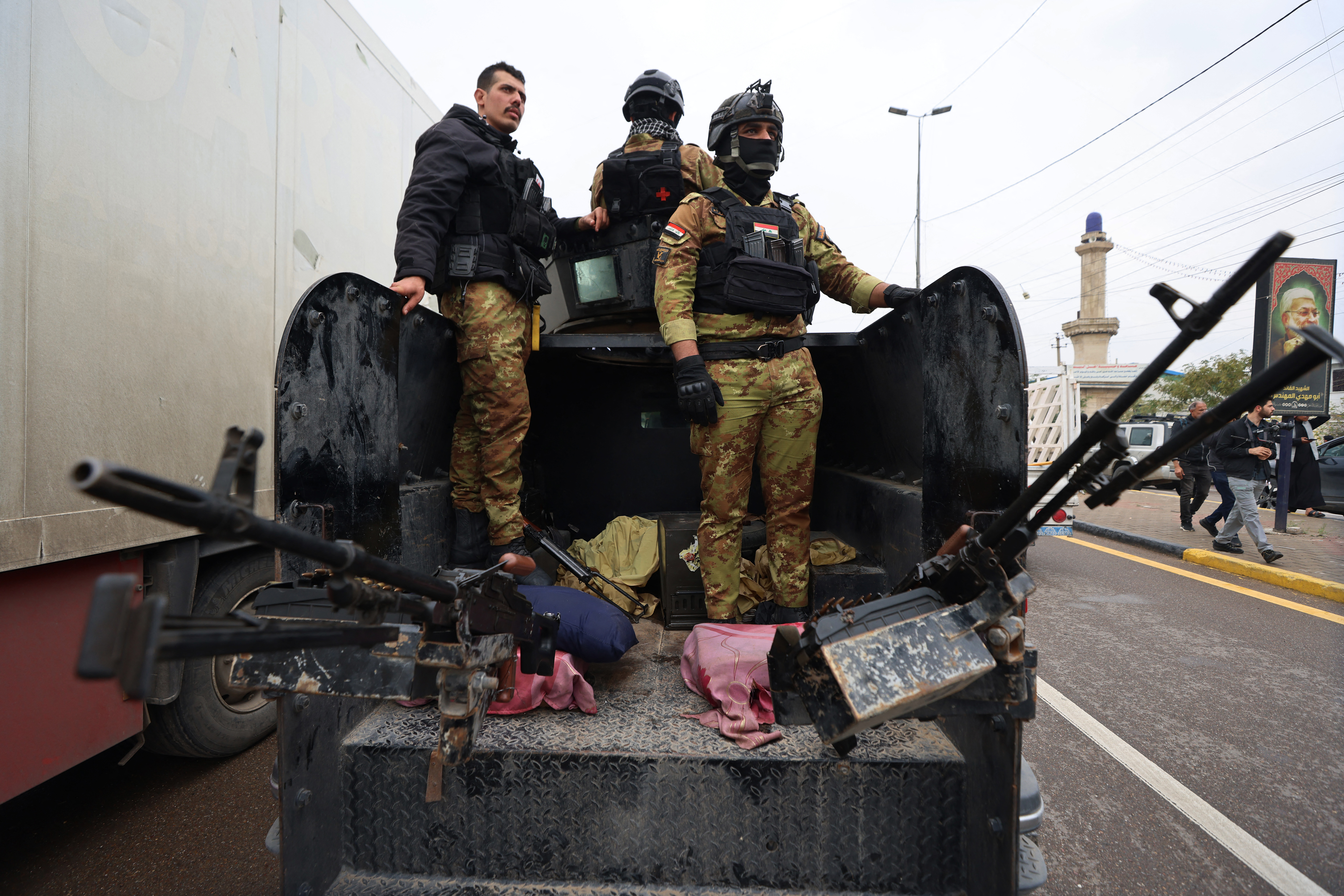 Members of Iraqs Hashed al-Shaabi, an alliance of factions now integrated into the regular army, guard the streets during the funeral for members of the Hashed al-Shaabi Forces in Baghdad on March 24, 2026. Fifteen fighters from the Hashd al-Shaabi were killed before dawn on March 24, in an American strike on Al-Anbar province in western Iraq, according to an updated death toll published by this alliance of former paramilitaries, which includes pro-Iranian groups. Iraq has been drawn into the Middle East war triggered by the US-Israel attack on its neighbour Iran on February 28. (Photo by AHMAD AL-RUBAYE / AFP)