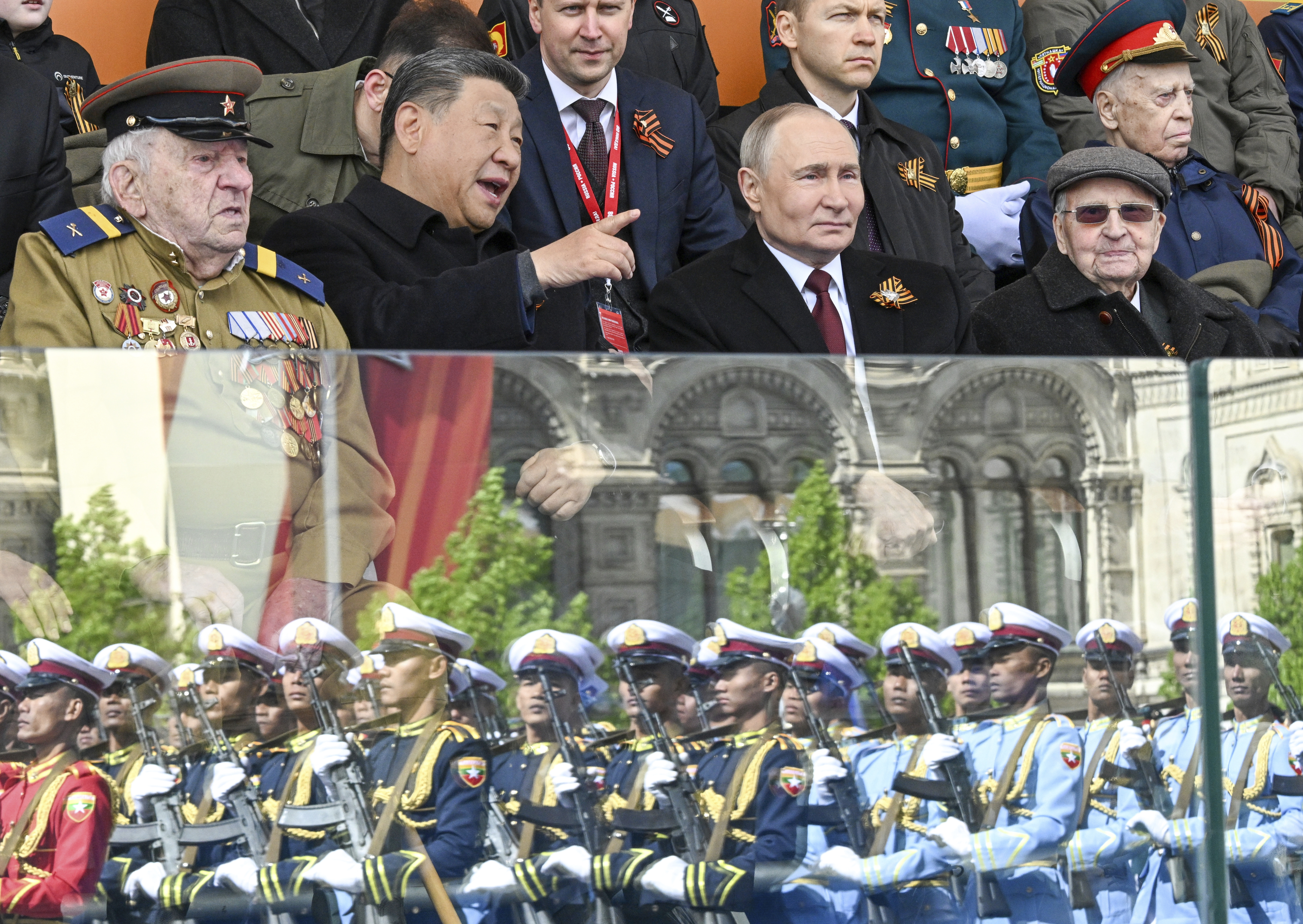 Russian President Vladimir Putin, centre right, and Chinese President Xi Jinping, centre left, talk as Myanmar's servicemen are reflected in a stand's glass, during the Victory Day military parade in Moscow, Russia, Friday, May 9, 2025, during celebrations of the 80th anniversary of the Soviet Union's victory over Nazi Germany during the World War II. (Sergei Bobylev/Photo host agency RIA Novosti via AP)