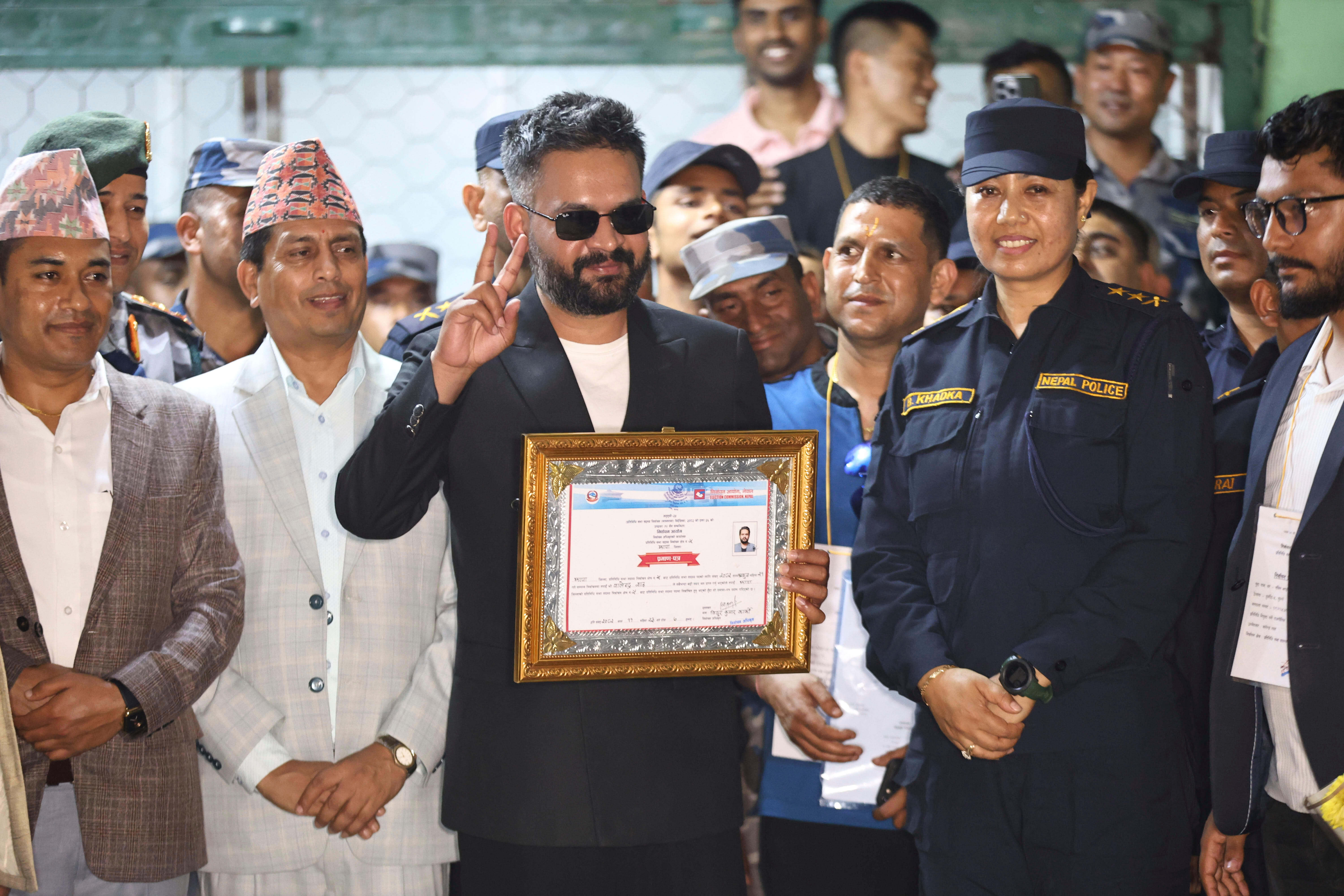 Balendra Shah, foreground, receives his victory certificate after election.