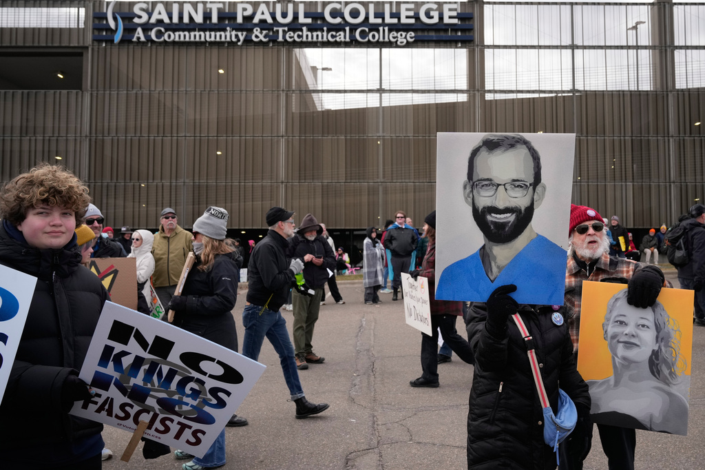 A protester holds a sign of a legal observer shot and killed by federal immigration agents