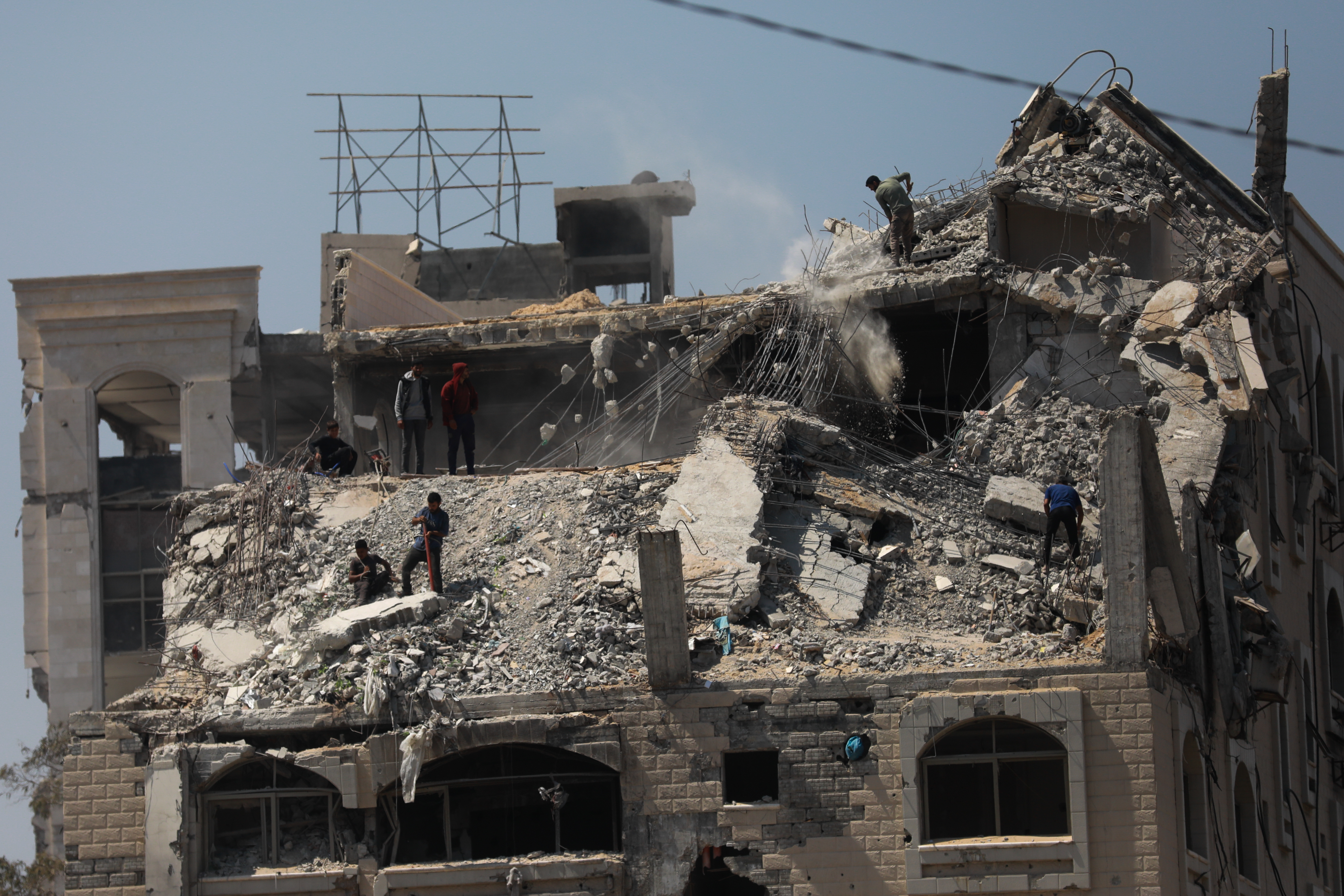 Workers on top of the rubble of a building