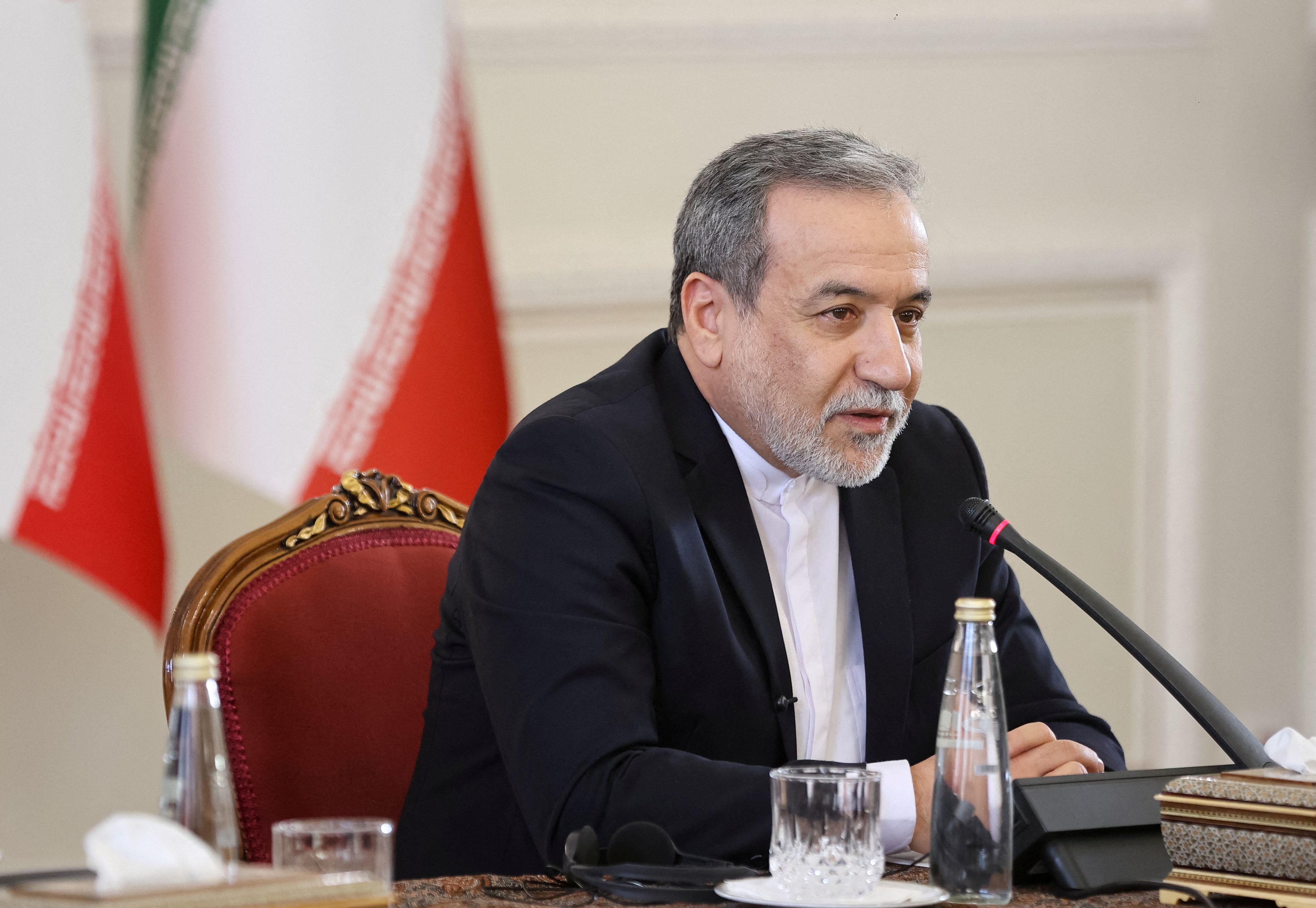 Araghchi with an Iranian flag behind him