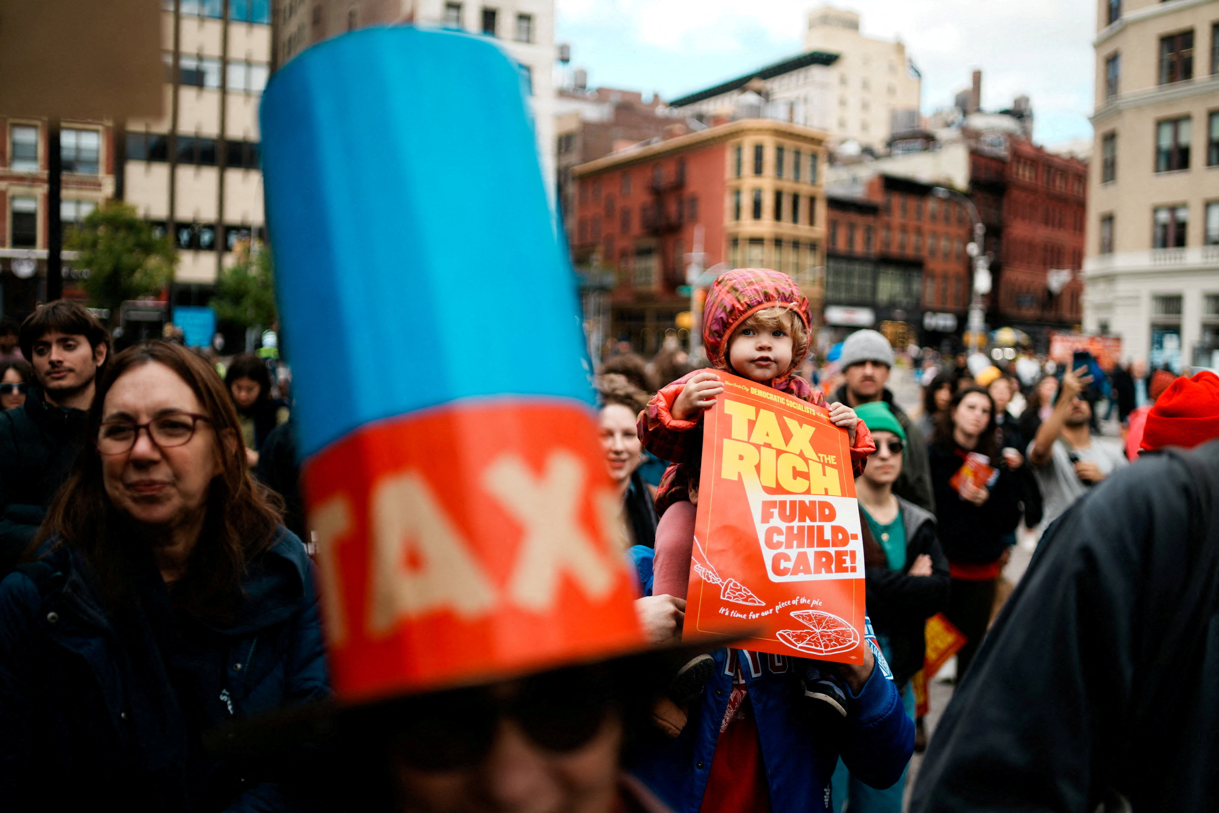 A child holds a poster as people take part in a "Tax the Rich" protest in New York City, U.S., November 16, 2025. [Eduardo Munoz/Reuters]