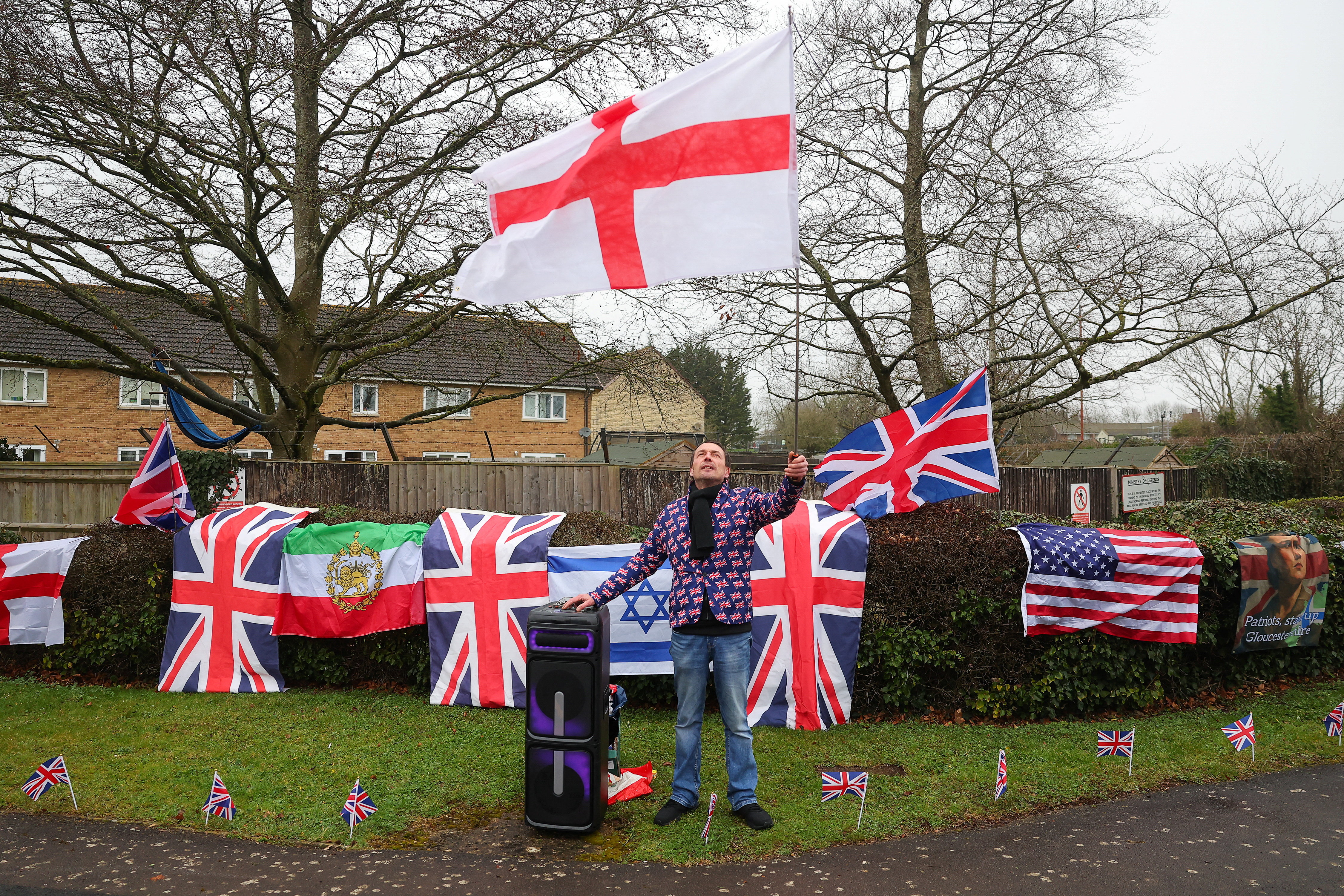 A man who described himself as a 'patriot counter-protester' and supports the U.S. and Israeli operation against Iran, wears a Union Jack-themed jacket while waving an England flag, as anti-war activists protest outside RAF Fairford, which hosts United States Air Force (USAF) personnel, amid the U.S.-Israeli conflict with Iran, in Fairford, Britain, March 7, 2026. REUTERS/Toby Melville