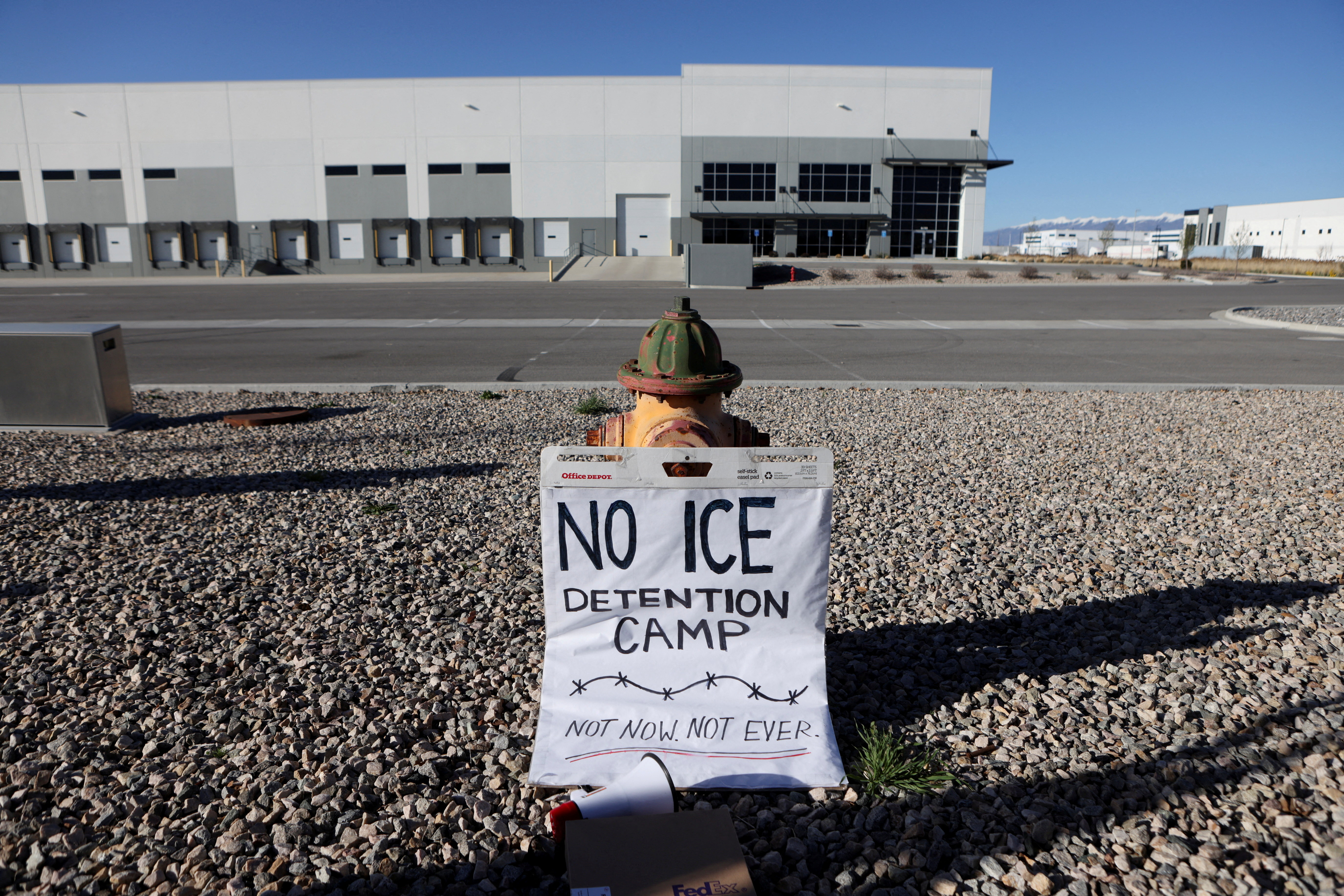 A placard is placed on the ground near a warehouse where people protest as it is purchased by U.S. Immigration and Customs Enforcement (ICE)