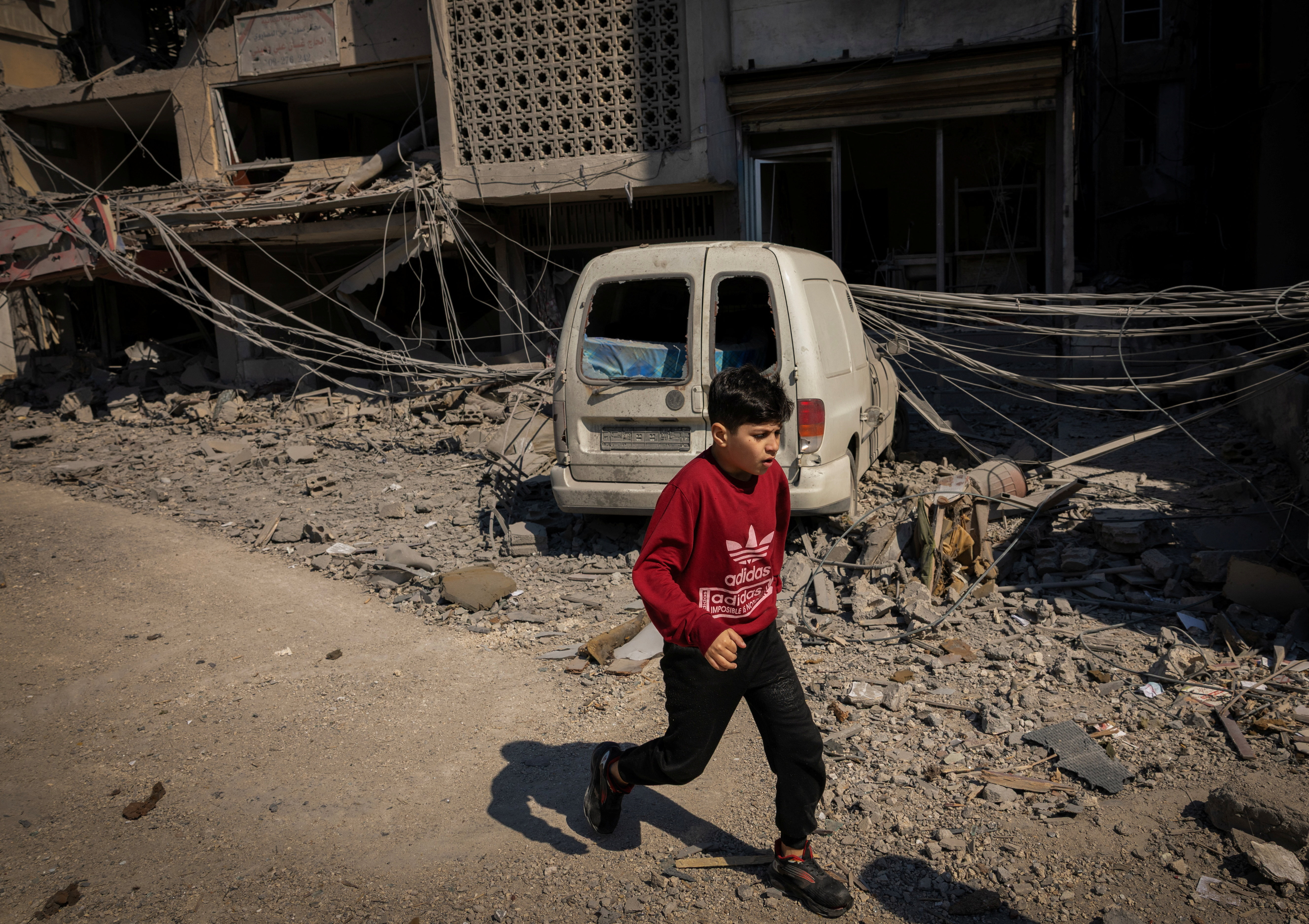 A boy runs past a damaged building at the site of an Israeli strike in Tyre, Lebanon, April 8,