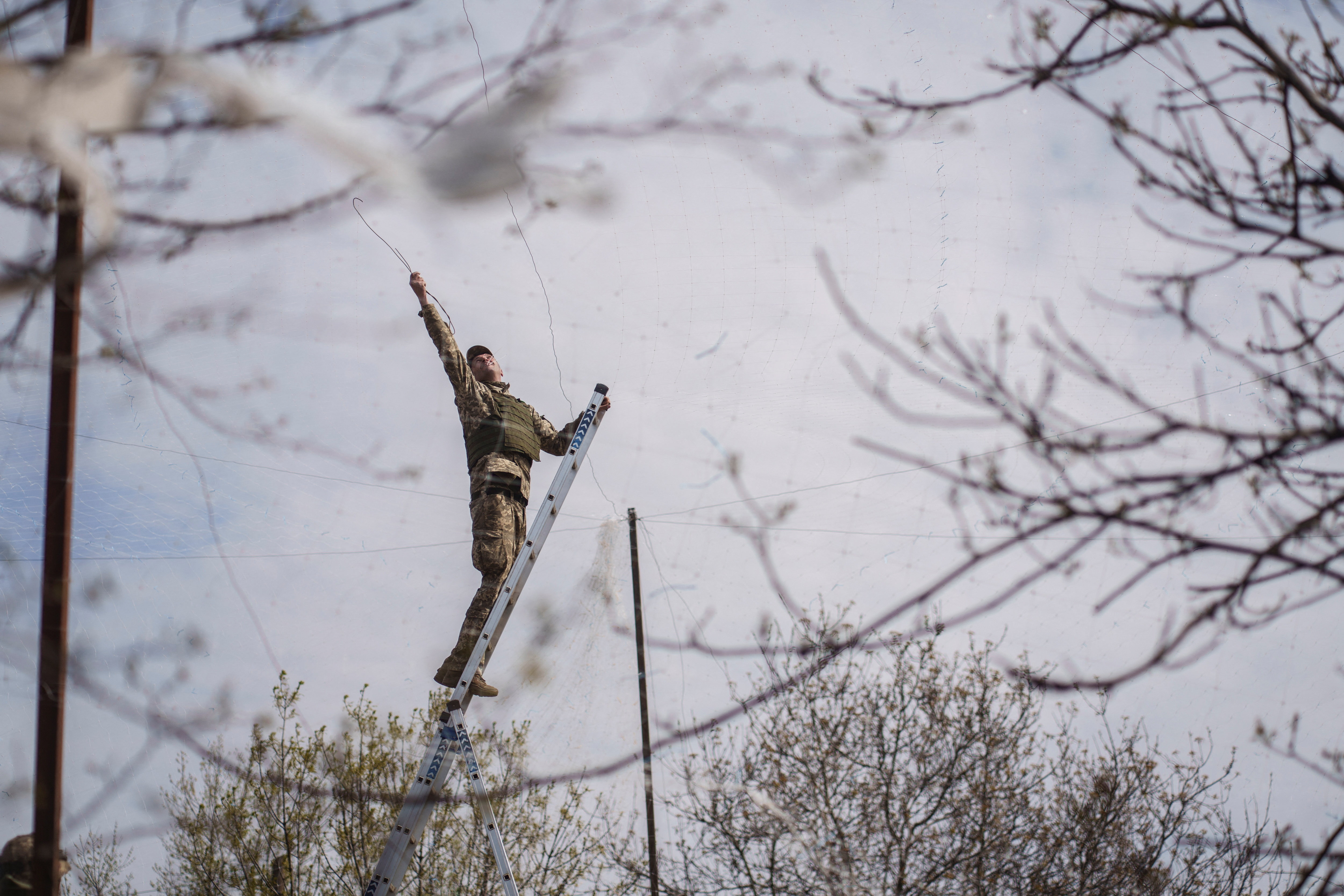 A serviceman of the Ukrainian Armed Forces installs anti-drone nets over a road near the frontline town of Druzhkivka, amid Russia's attack on Ukraine, in Donetsk region, Ukraine April 28, 2026. REUTERS/Serhii Korovainyi TPX IMAGES OF THE DAY