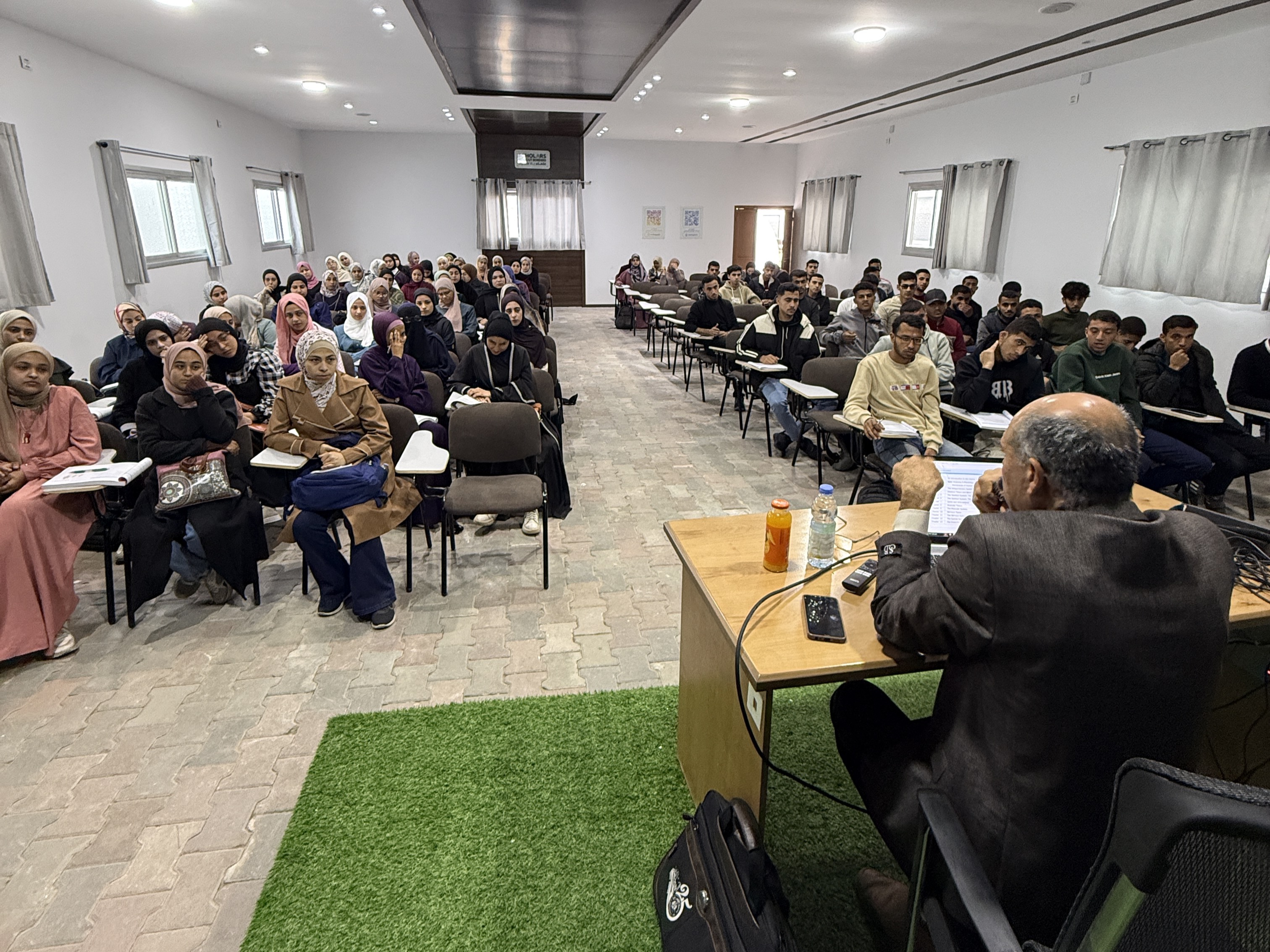 Dr Essam Mughari, a professor at the Palestine College of Nursing, gives a lecture at Gaza’s University City [Courtesy of Scholars Without Borders]