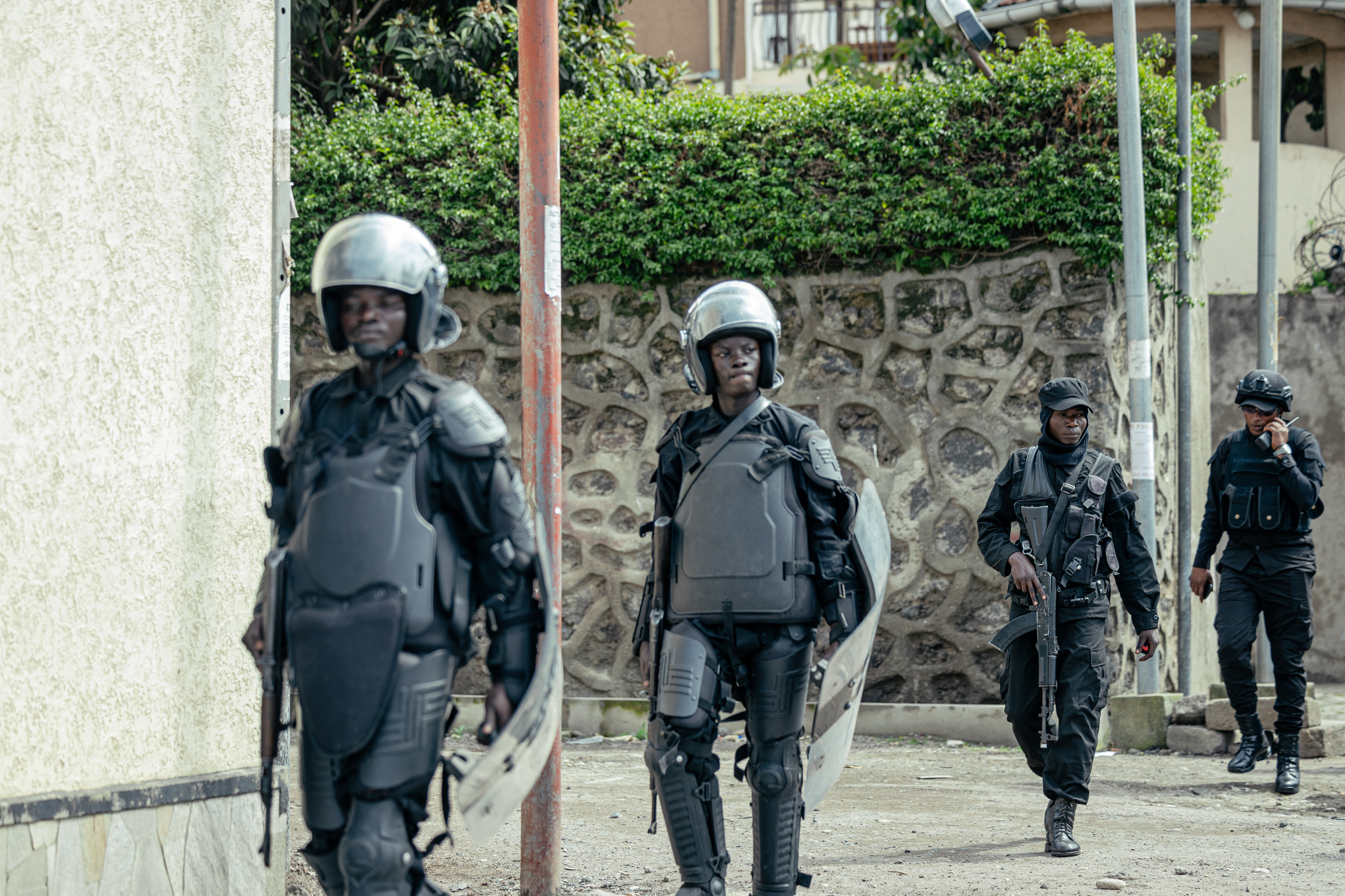 Members of the M23 wearing riot gear stand guard in a street.
