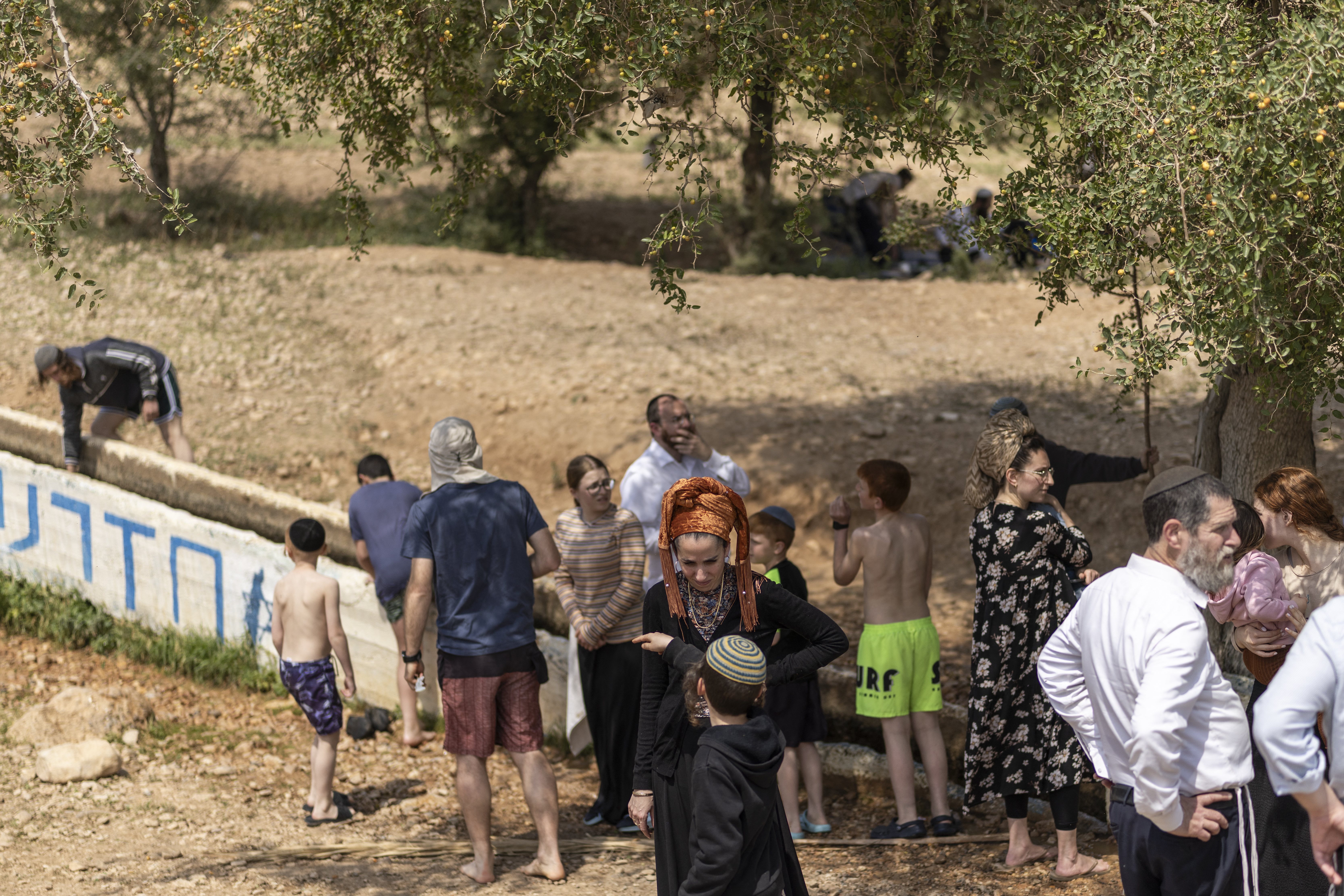 Israeli settlers stand at a water slide in the Israeli-occupied West Bank village of Ras Ein al-Auja on April on April 9, 2026. Israel vowed more strikes against Hezbollah on April 9, dismissing mounting international demands that the fragile truce between the United States and Iran in the Gulf be expanded to cover the war in Lebanon. (Photo by Ilia YEFIMOVICH / AFP)