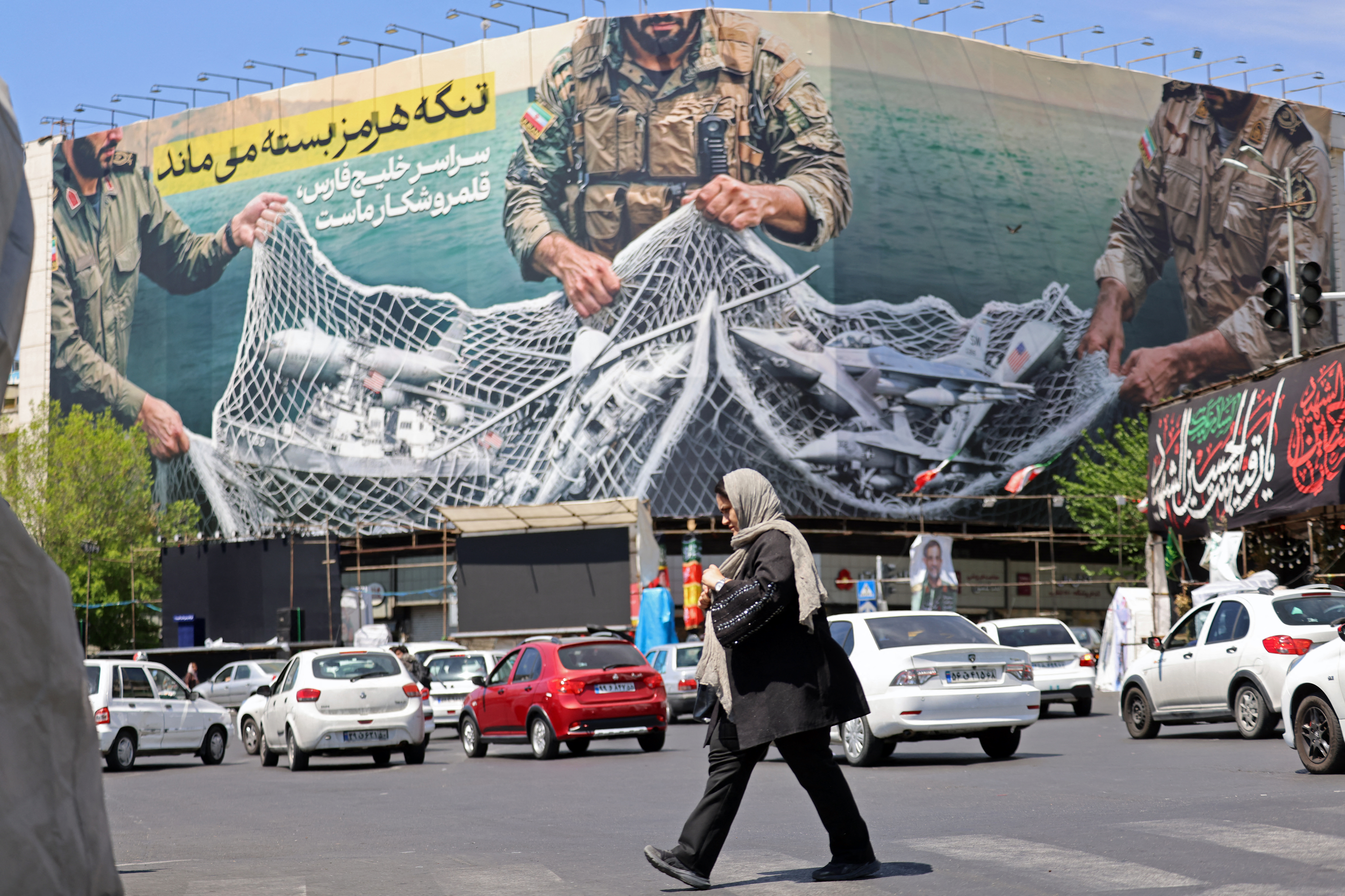 A woman walks past a giant billboard reading 'The Strait of Hormuz remains closed' at the Revolution Square in Tehran, Iran on April 12, 2026.