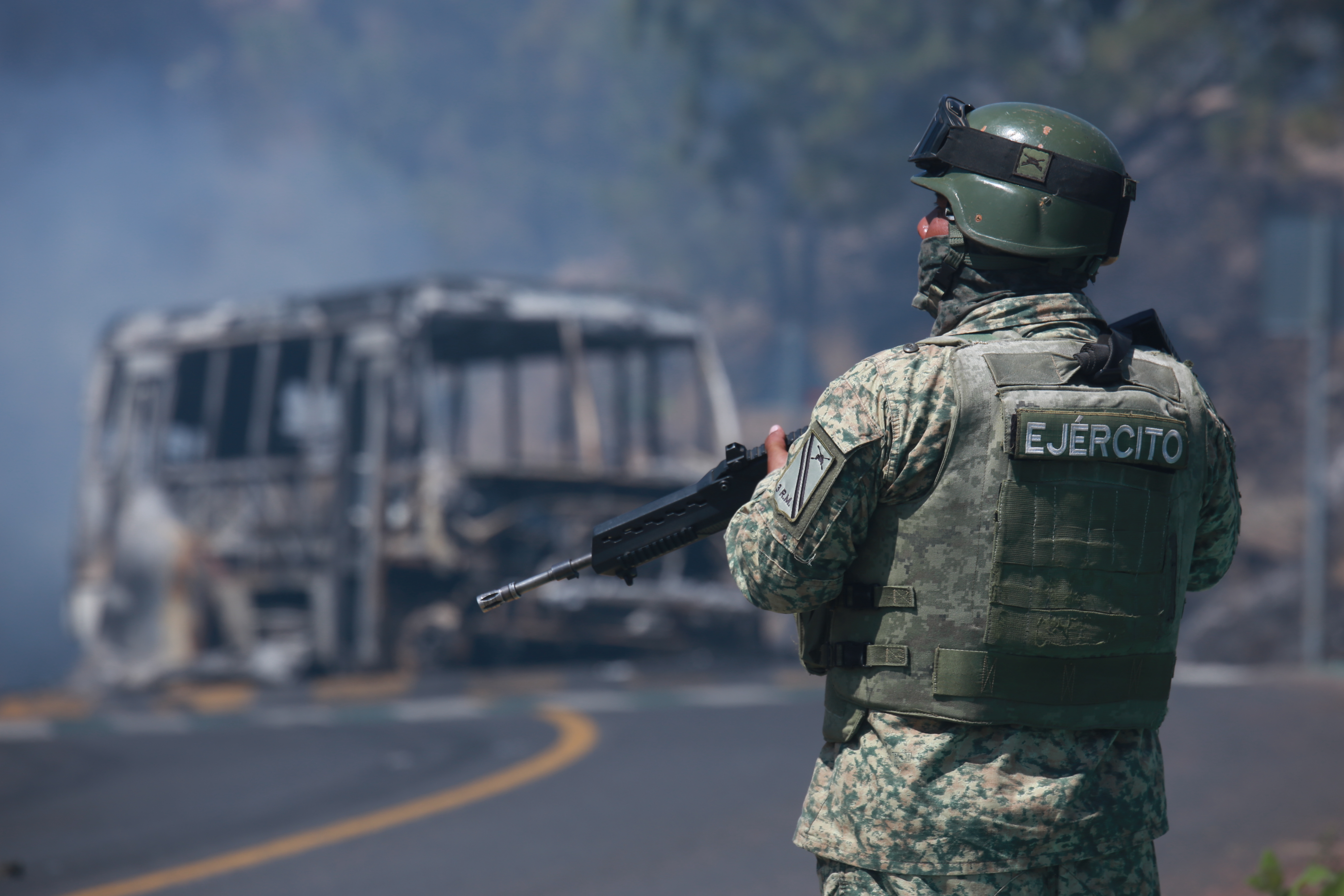 A soldier stands guard by a charred vehicle after it was set on fire in Cointzio, Michoacán state, Mexico, Sunday, Feb. 22, 2026, after the death of the leader of the Jalisco New Generation Cartel, Nemesio Rubén Oseguera Cervantes, known as "El Mencho."
