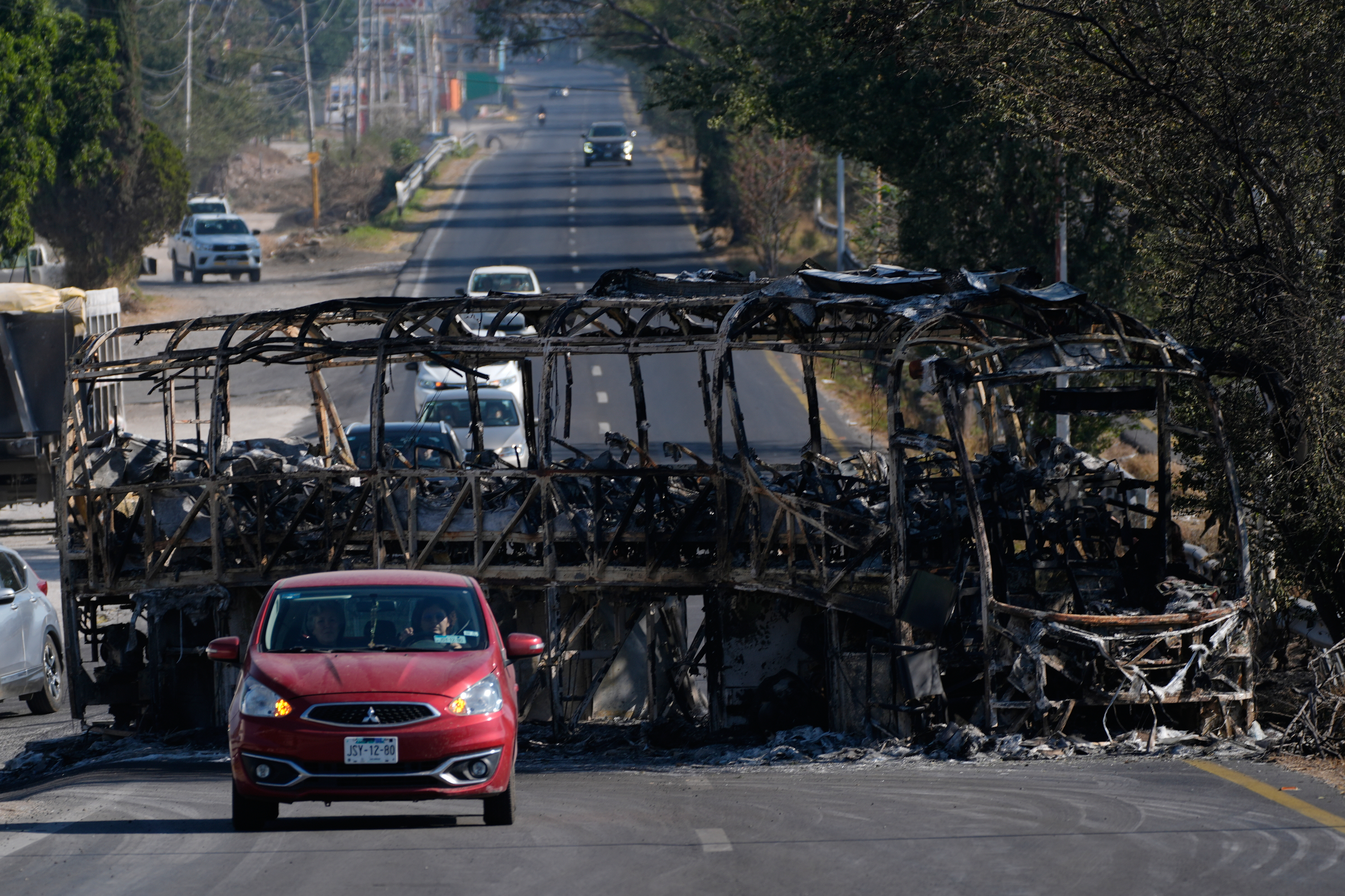 Vehicles drive past a charred bus the day after the Mexican army killed Jalisco New Generation Cartel leader Nemesio Oseguera Cervantes, known as "El Mencho," in Guadalajara, Mexico