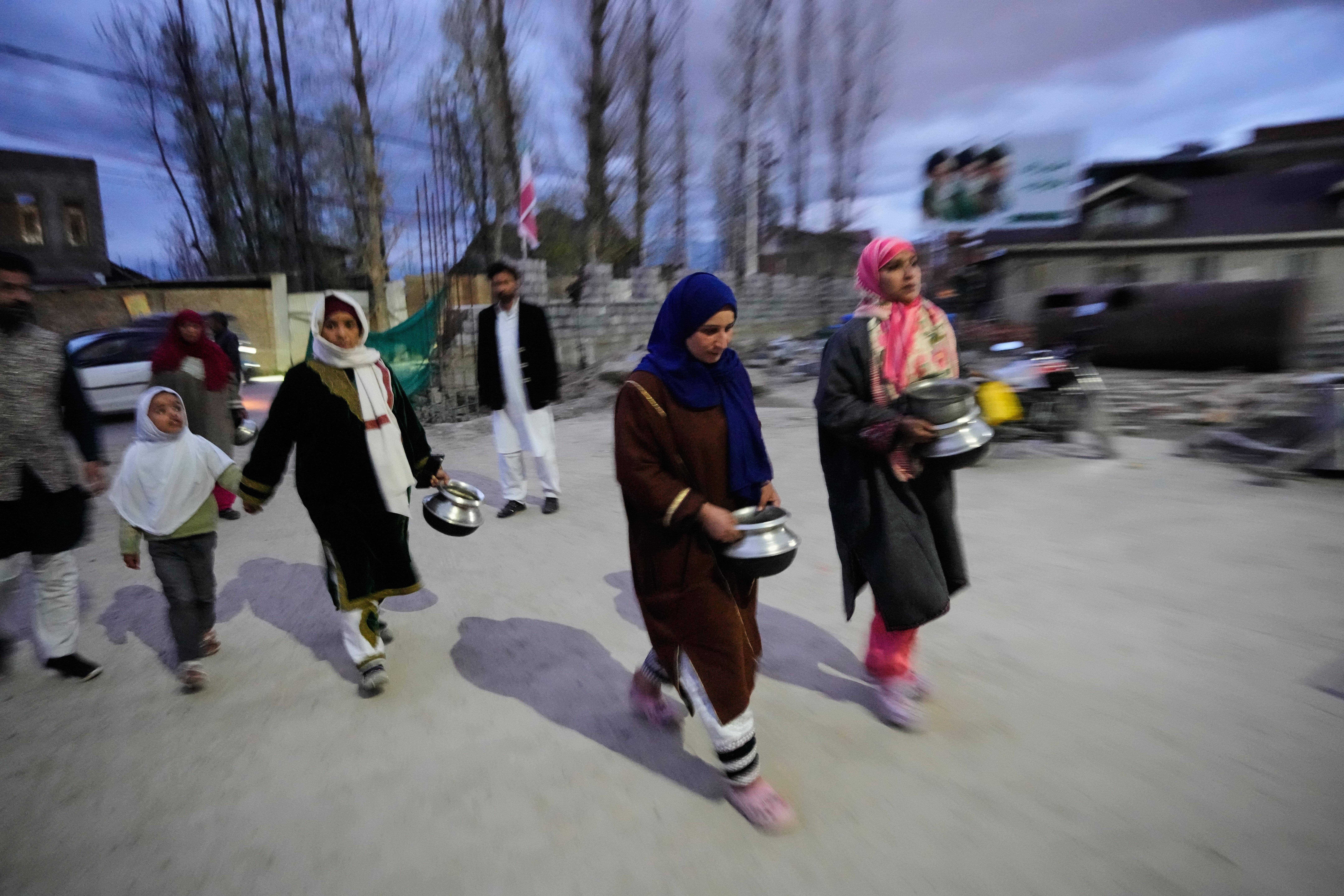 Shiite Muslim women arrive carrying kitchenware to donate at a relief drive for Iran in Budgam, Indian-controlled Kashmir, Monday, March 23, 2026. (AP Photo/Mukhtar Khan)