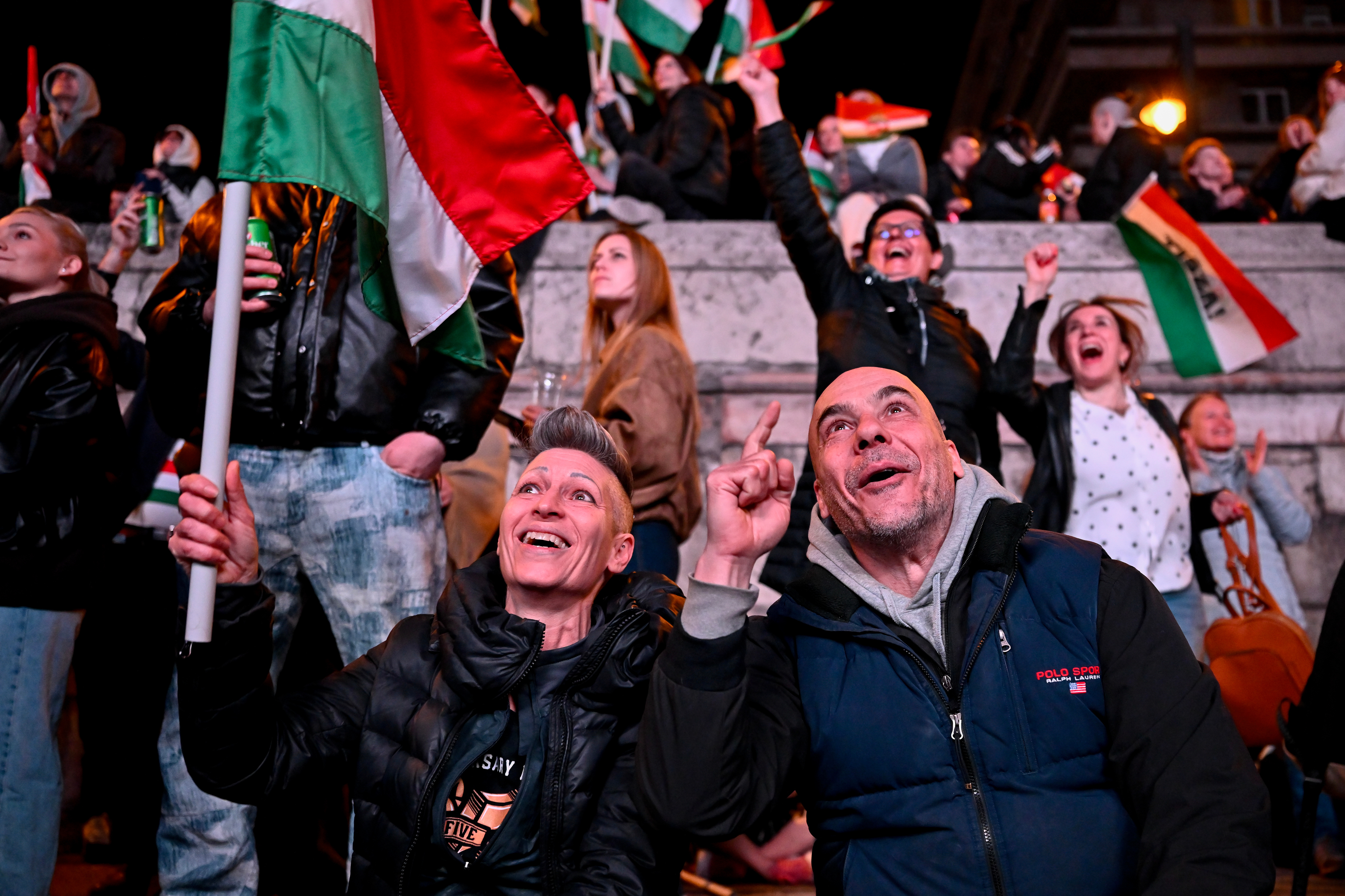 People react in the streets after the announcement of partial results of Hungary's parliamentary elections in Budapest on April 12, 2026.