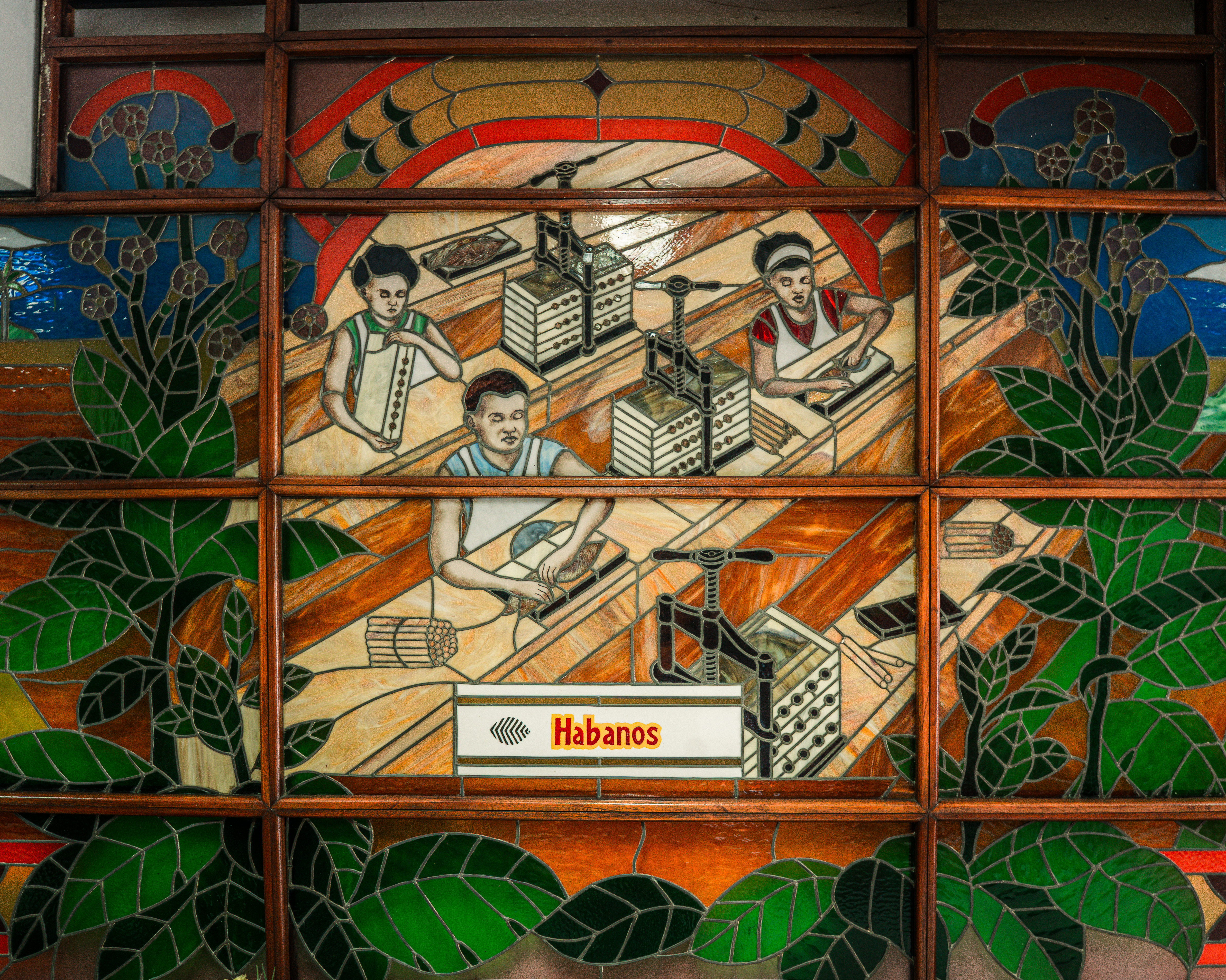 Torecedores - Cuban cigar rollers - depicted in a stained-glass mural on the wall of Havana’s La Corona cigar factory. Fuel shortages, economic crisis and mass emigration have depleted the workforce, with some factories that once employed 400 workers now operating with just 80. [Euan Wallace/ Al Jazeera]
