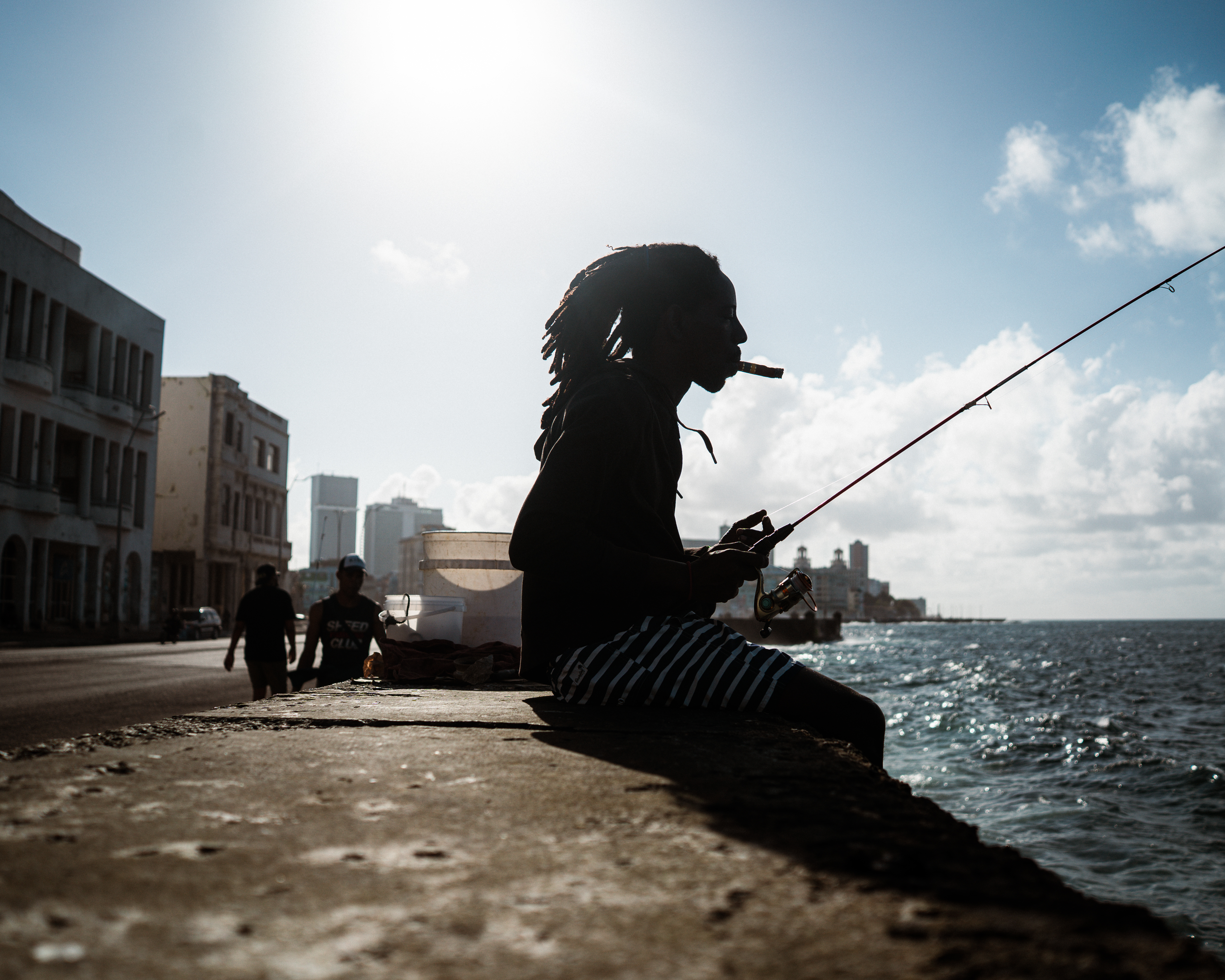 A Havana local smokes a cigar whilst fishing on the Malecón. [Euan Wallace/ Al Jazeera]