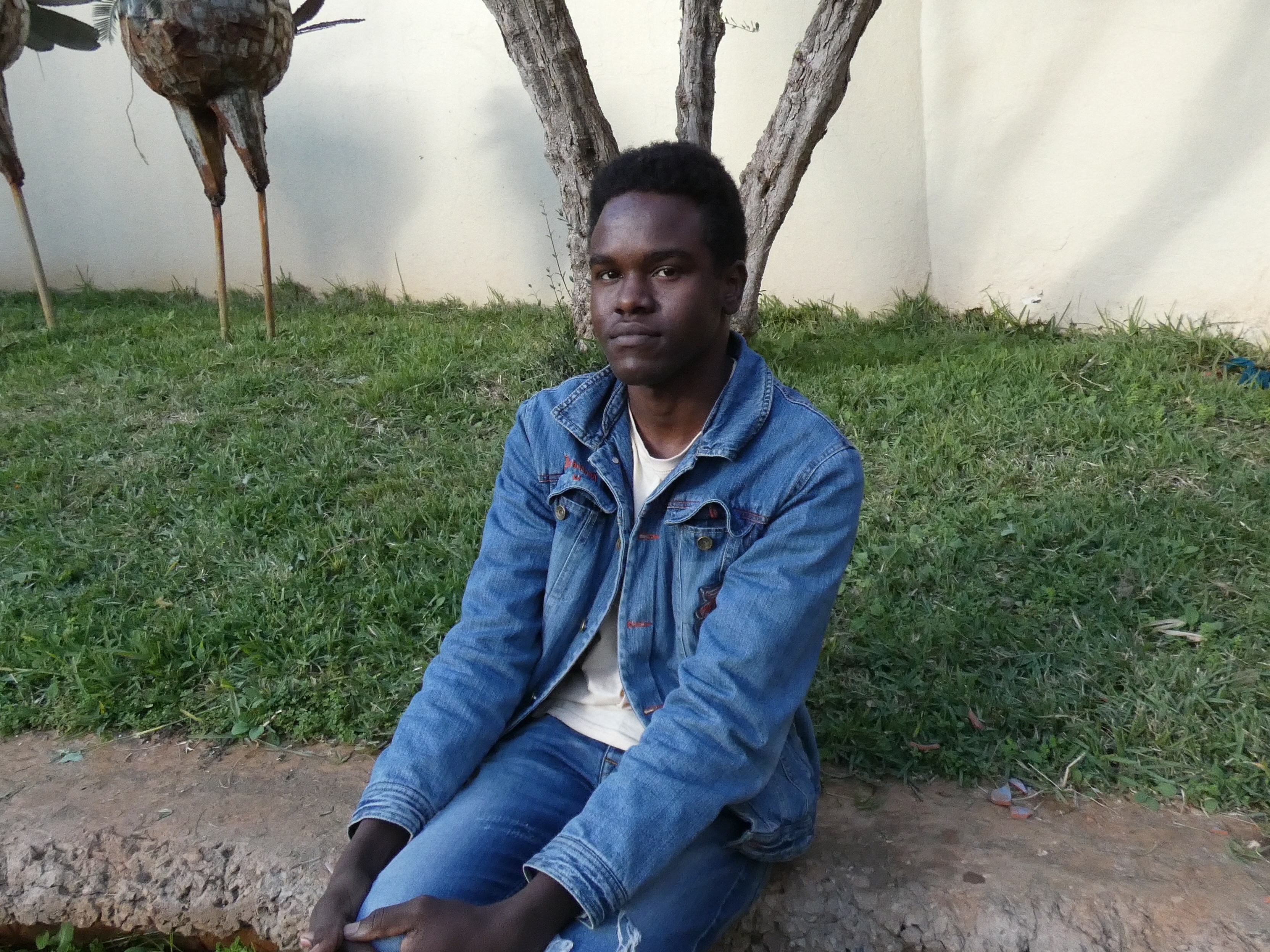 Sudanese refugee Amir Ali sitting on a wall.