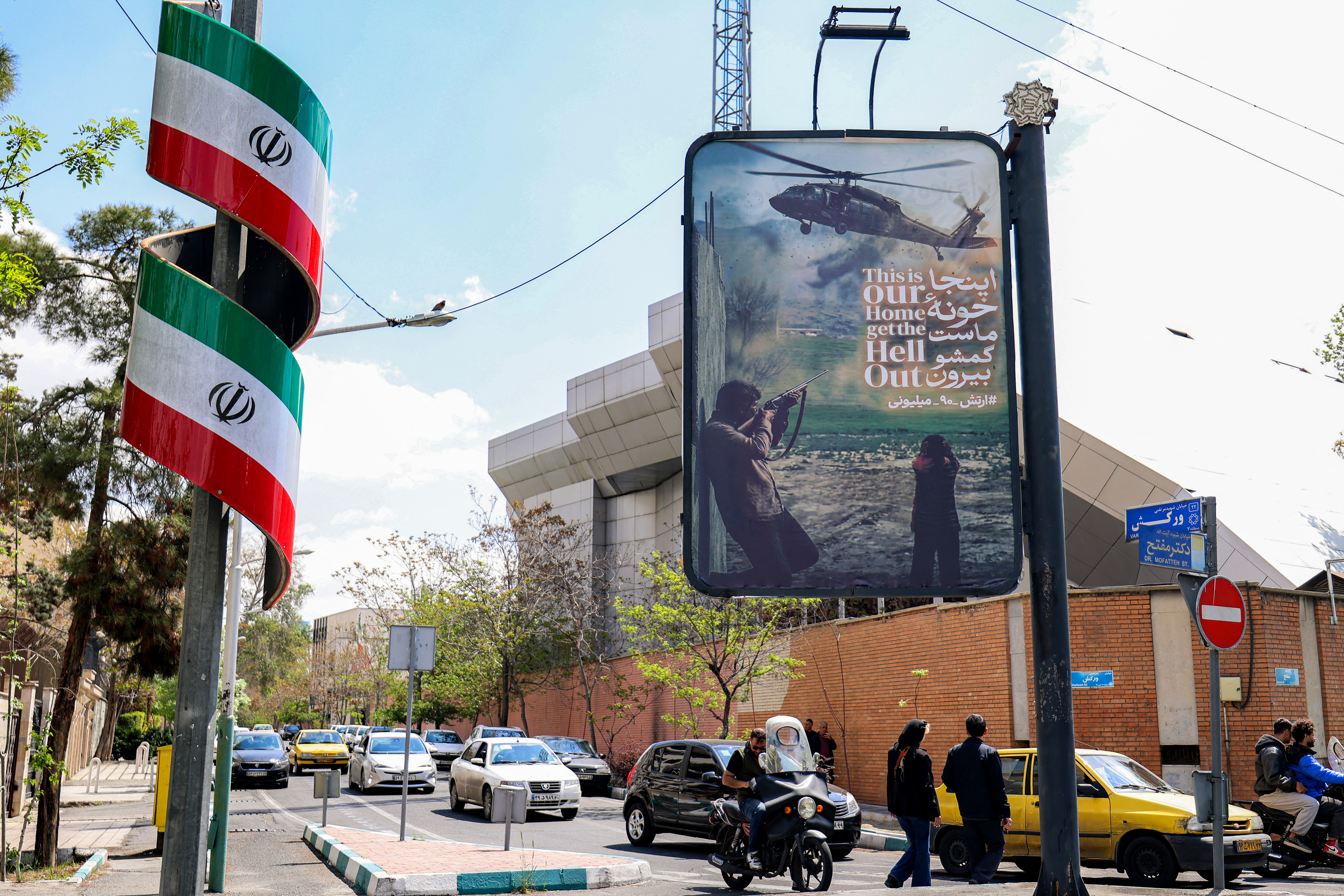 An anti-US banner depicting a helicopter being fired upon is displayed along a street in Tehran, Iran