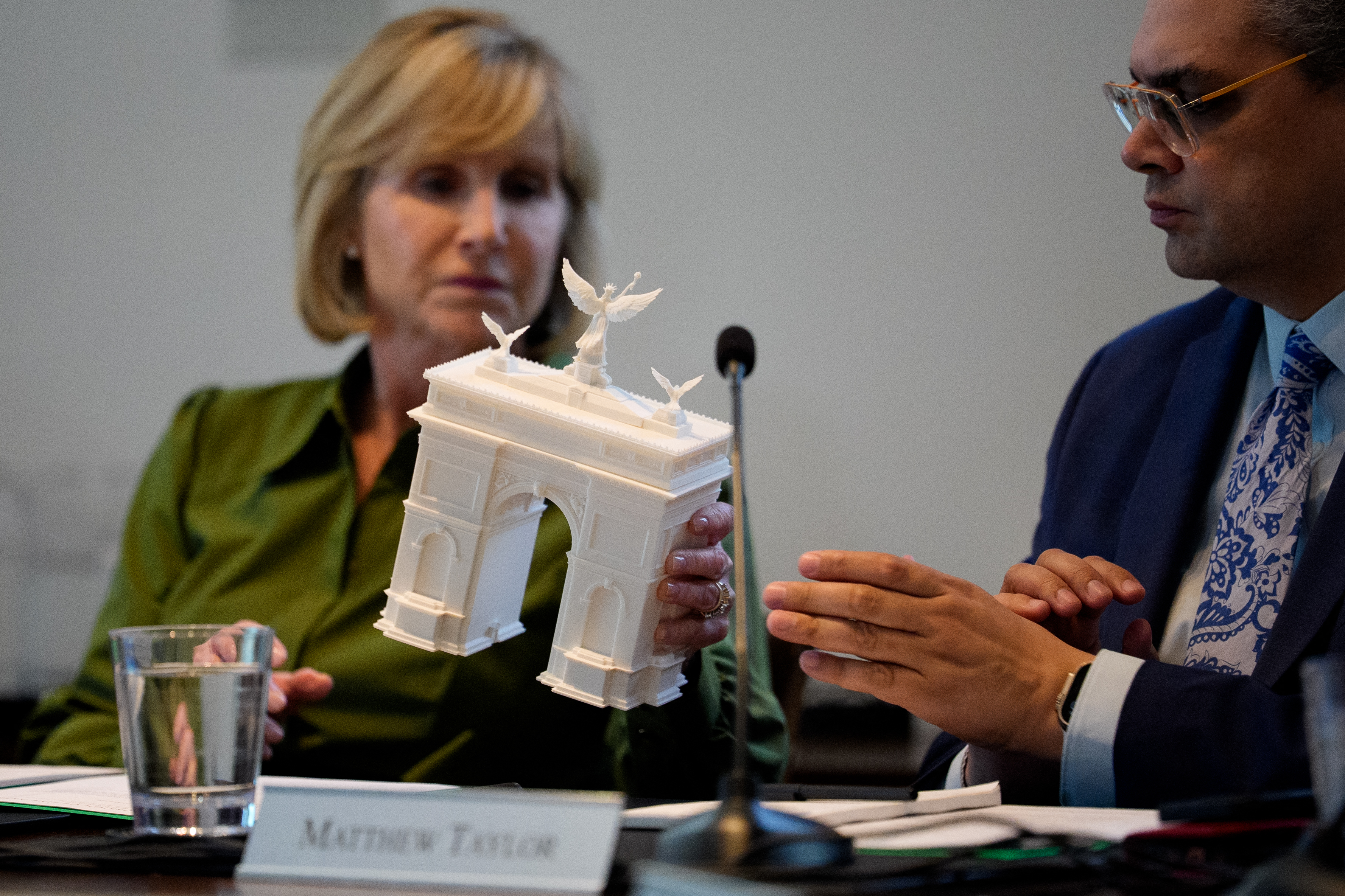 A member of a panel holds a model of a triumphal arch