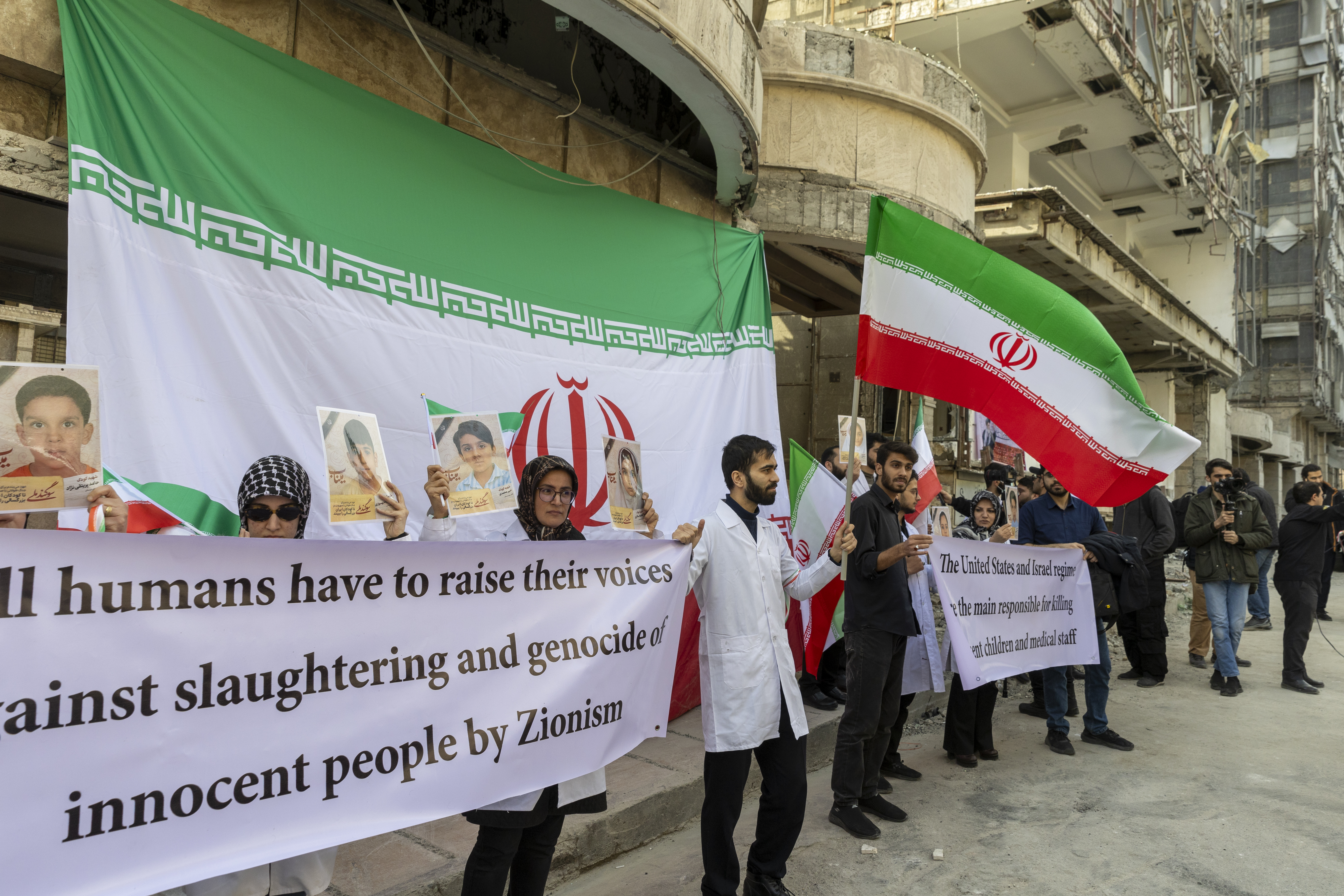 TEHRAN, IRAN - MARCH 7: People hold flags and banners at a protest by medical professionals outside Gandhi Hospital, which was damaged in an airstrike earlier in this week, on March 7, 2026 in Tehran, Iran. The United States and Israel continued their joint attack on Iran that began on February 28. Iran retaliated by firing waves of missiles and drones at Israel, and targeting U.S. allies in the region. (Photo by Majid Saeedi/Getty Images)