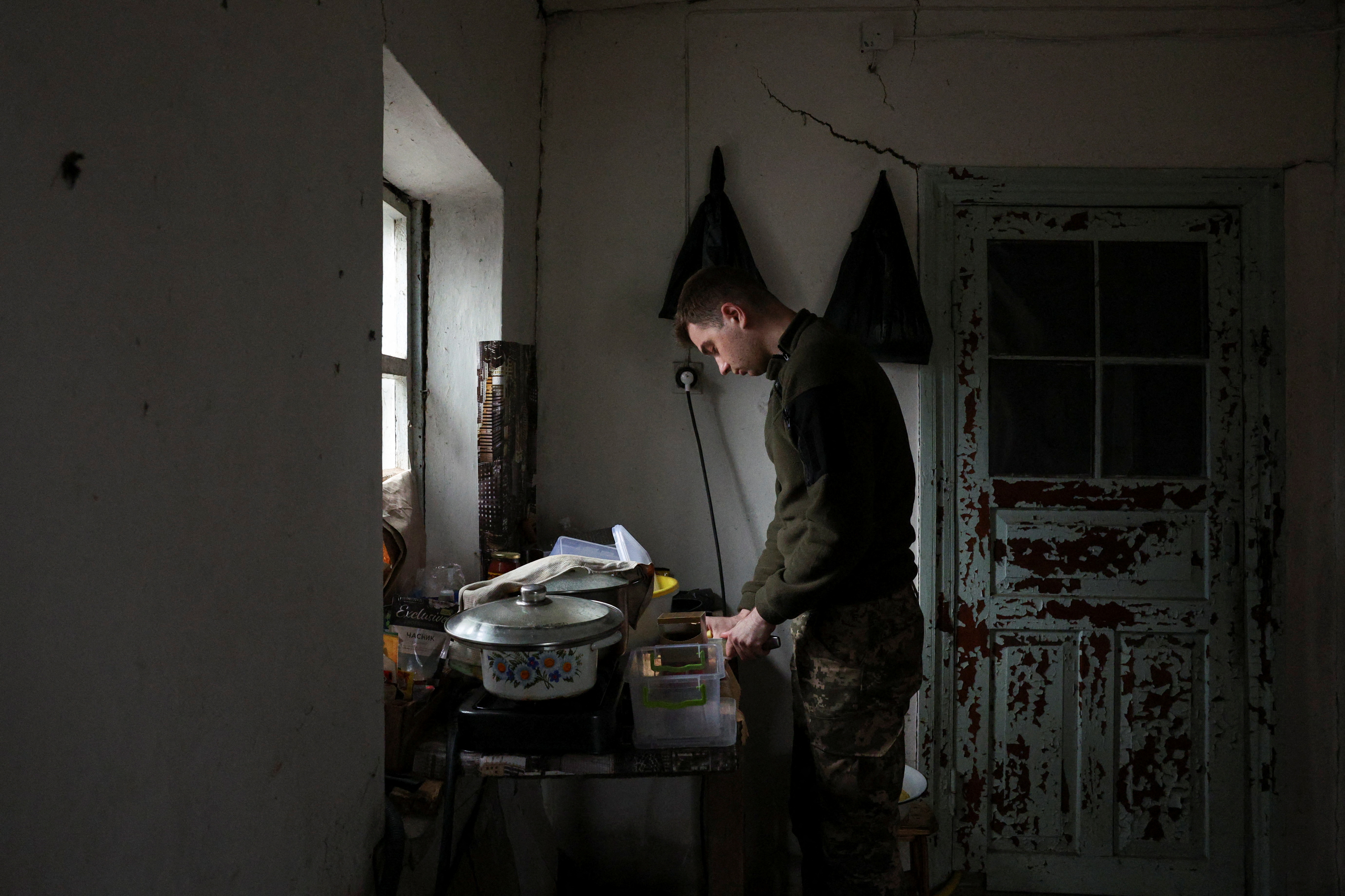 A soldier of the 59th Assault Brigade on rotation out of the eastern combat zone cooks food at a resting house during a five-day leave in the rear of the frontlines at an undisclosed location in the Dnipropetrovsk region before returning to the Pokrovsk defence effort, amid Russia's attack on Ukraine, Ukraine April 1, 2025. REUTERS/Violeta Santos Moura