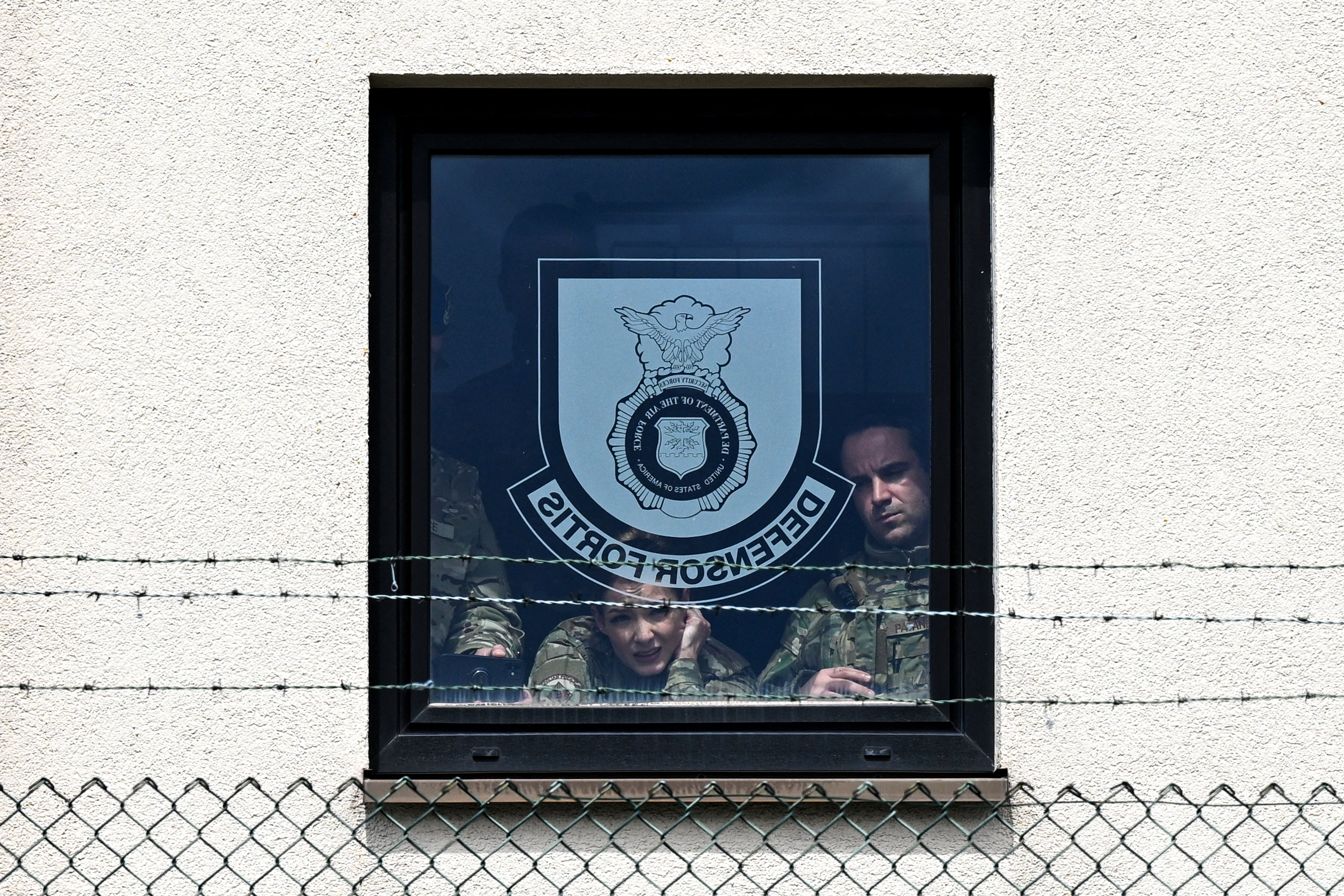 Soldiers stare out of a window at a US military base