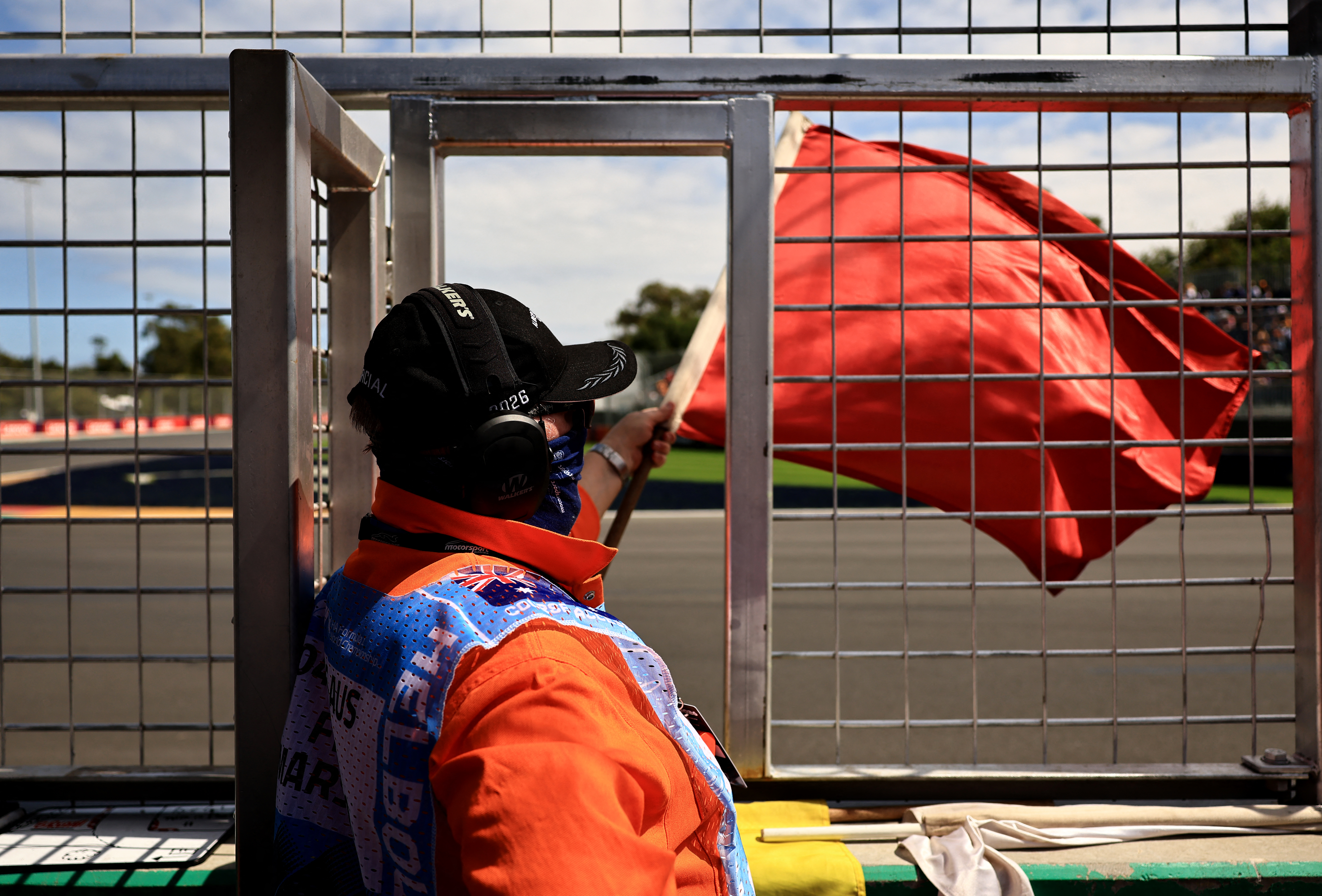 A race marshal waves a red flag at a motorsport meeting following a crash