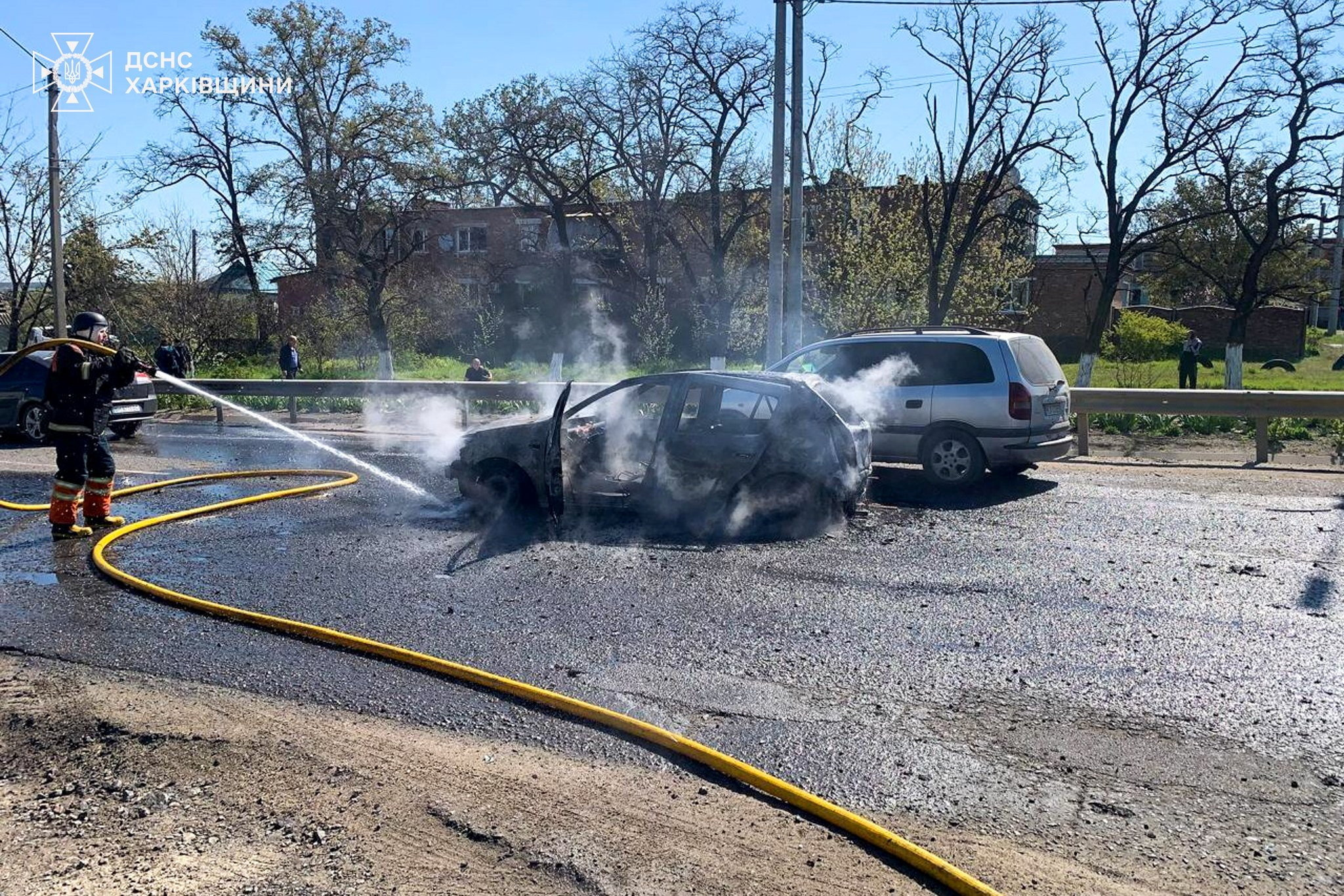 Firefighter using a hose to extinguish a burning car in Ukraine