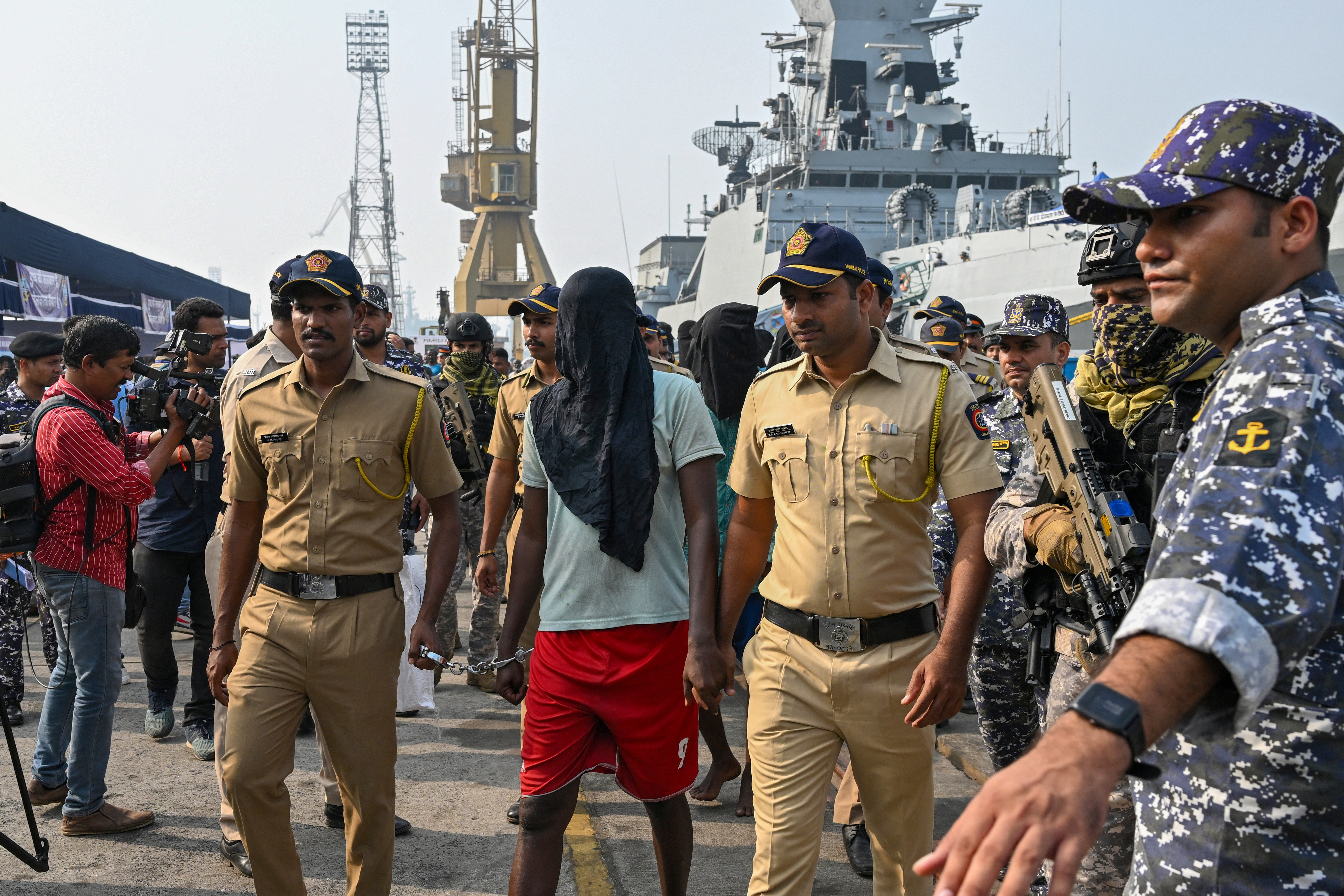 Policemen escort an accused Somali pirate to board a police van at the Indian naval dockyard in Mumbai on March 23, 2024. India brought 35 accused Somali pirates to Mumbai on March 23, days after they were apprehended when naval commandos recaptured a hijacked bulk carrier and rescued several hostages. [Indranil Mukherjee/AFP]
