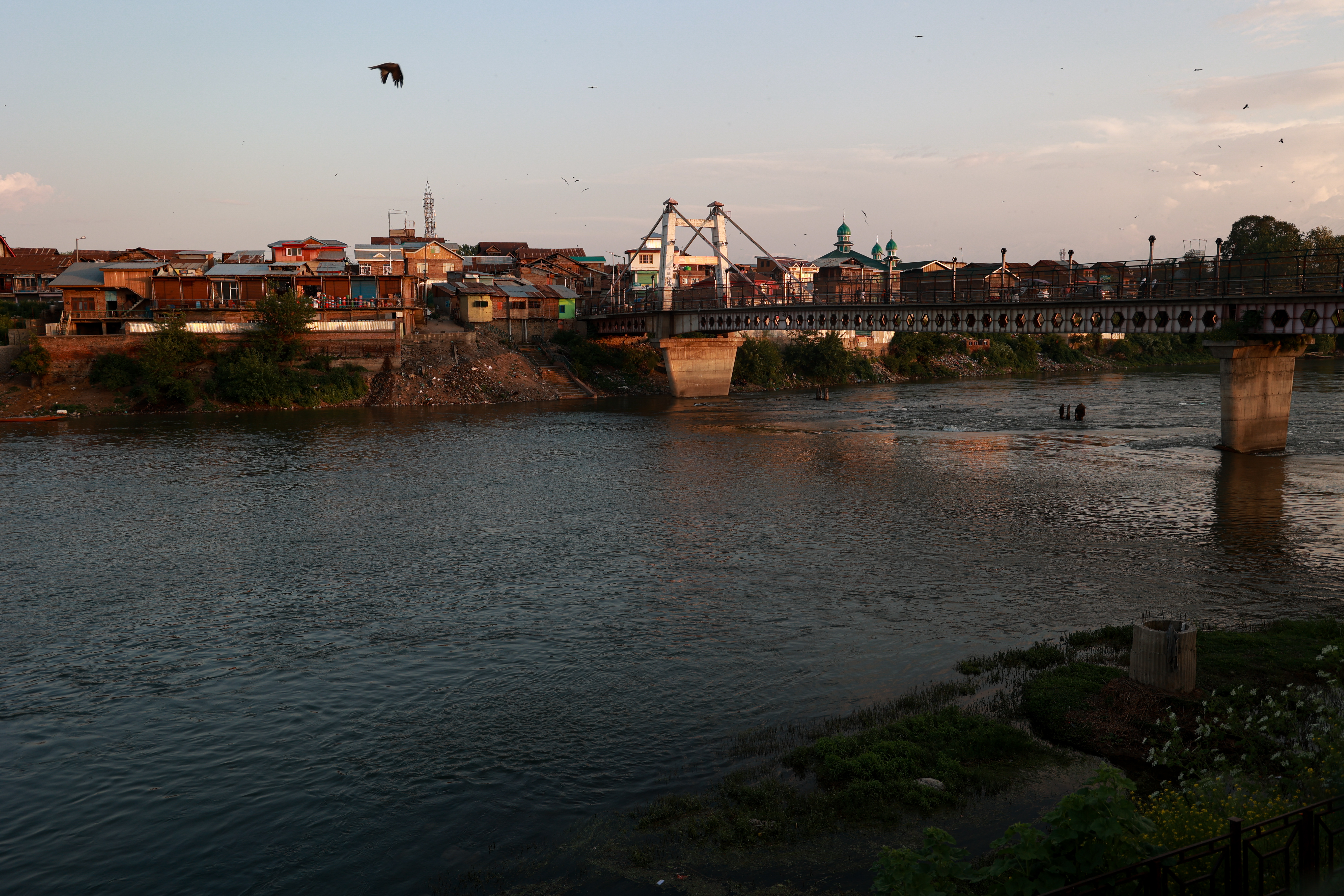 People walk on a bridge built on the River Jhelum in Sopore, Jammu and Kashmir, India, on May 7, 2026. The Jhelum River flows through India and Pakistan under the framework of the Indus Water Treaty, with recent tensions and border conflicts renewing scrutiny over its water-sharing provisions. (Photo by Nasir Kachroo/NurPhoto via Getty Images)