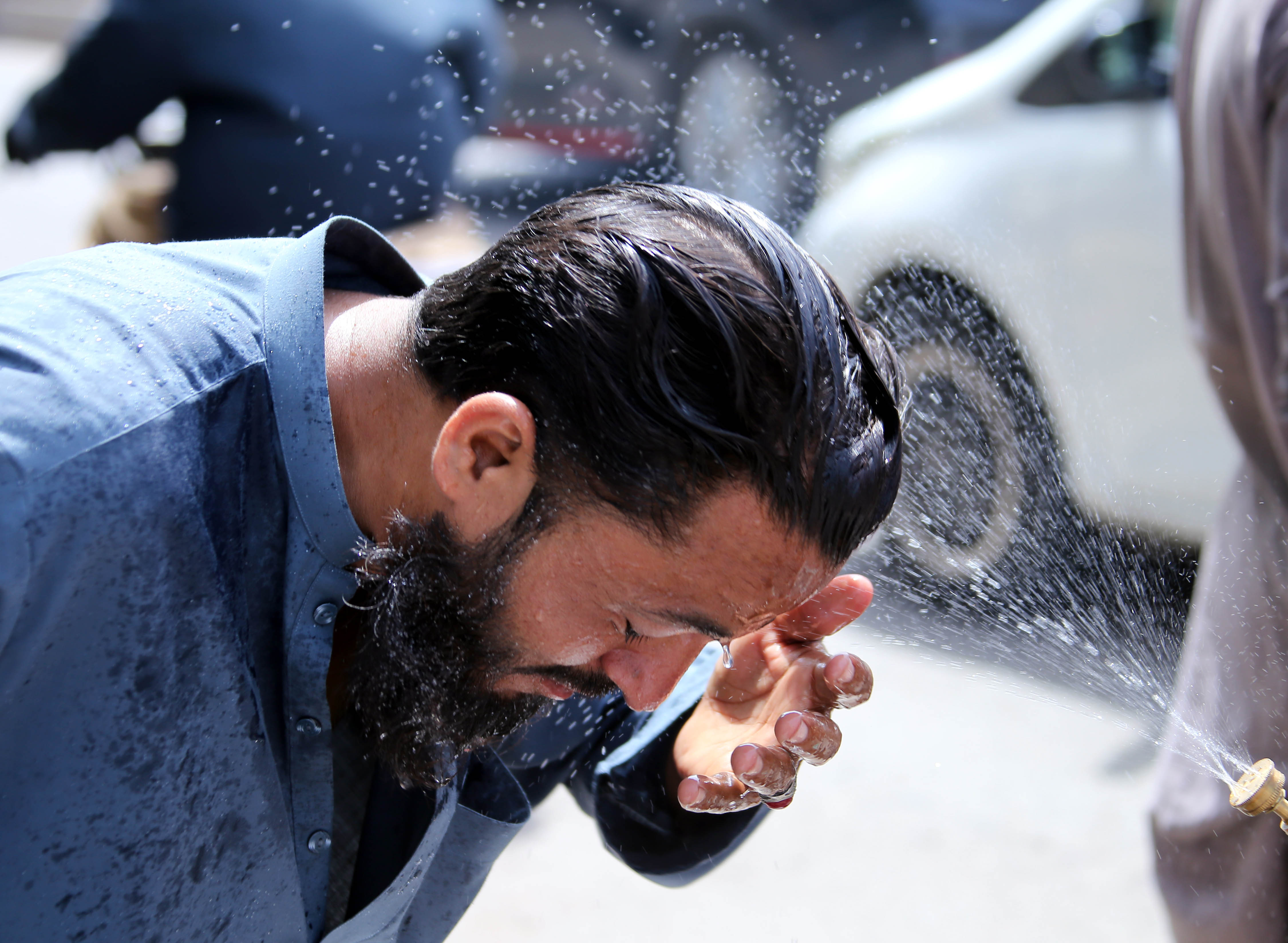 epa12934290 A volunteer sprays water on people as refreshment during a heatwave in Karachi, Pakistan, 05 May 2026. Karachi is expected to remain hot and dry over the next 24 hours, with temperatures below 40 degrees Celsius, the Pakistan Meteorological Department said, following a 44.1 degrees Celsius peak, as residents are advised to limit exposure and stay hydrated. EPA/REHAN KHAN