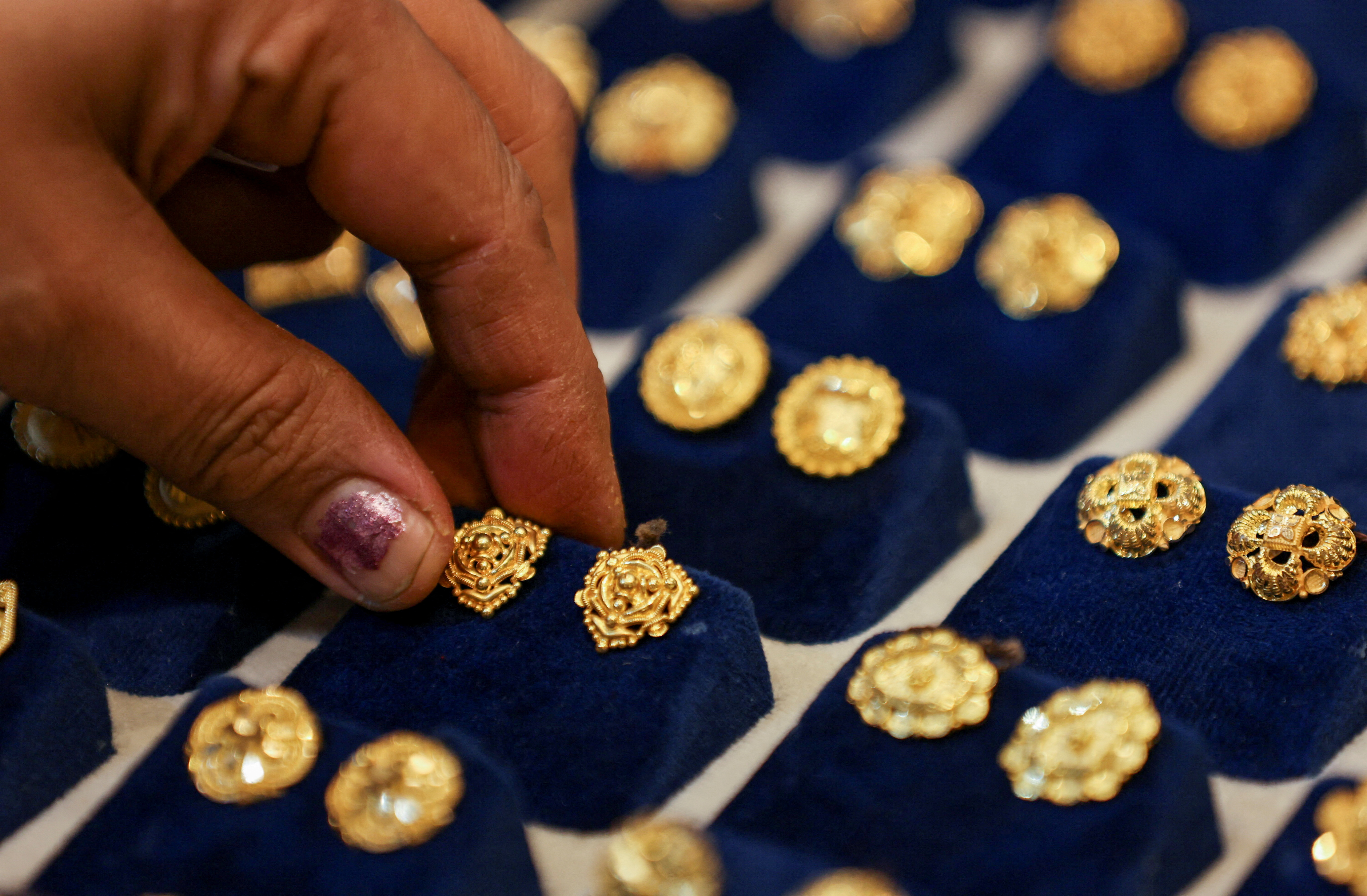 FILE PHOTO: A woman picks a gold earring at a jewellery shop in the old quarters of Delhi, India, May 24, 2023. REUTERS/Anushree Fadnavis/File Photo