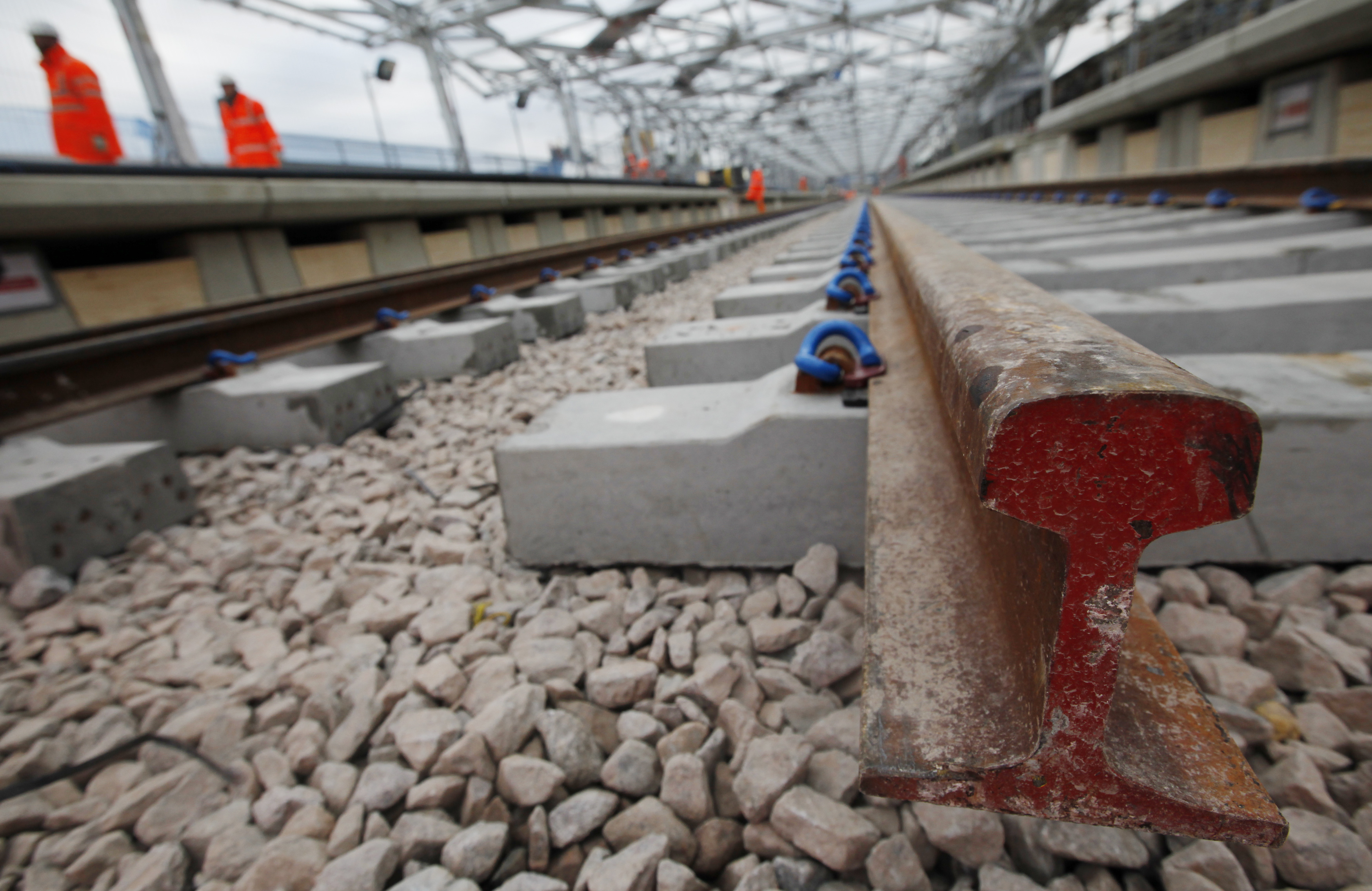 Construction workers walk near newly laid tracks at Blackfriars Train Station on Blackfriars bridge in London November 25, 2010. Britain will invest 6 billion pounds ($9.46 billion) in the Thameslink railway linking the south coast of England and towns north of London, Hammond said on Thursday. REUTERS/Suzanne Plunkett (BRITAIN - Tags: TRANSPORT BUSINESS CONSTRUCTION POLITICS)