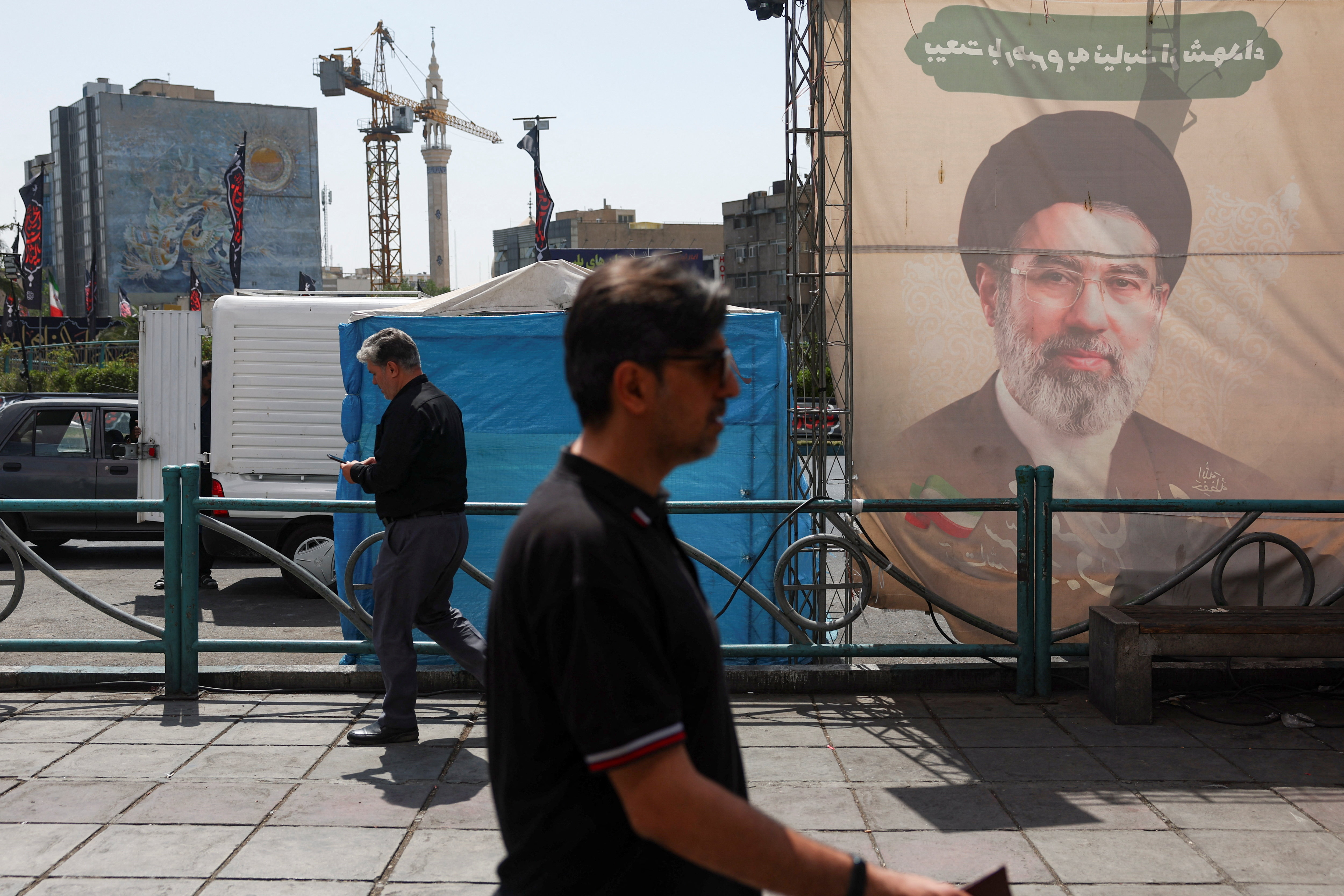 People walk past a banner with a picture of Iran's Supreme Leader, Mojtaba Khamenei, in Tehran