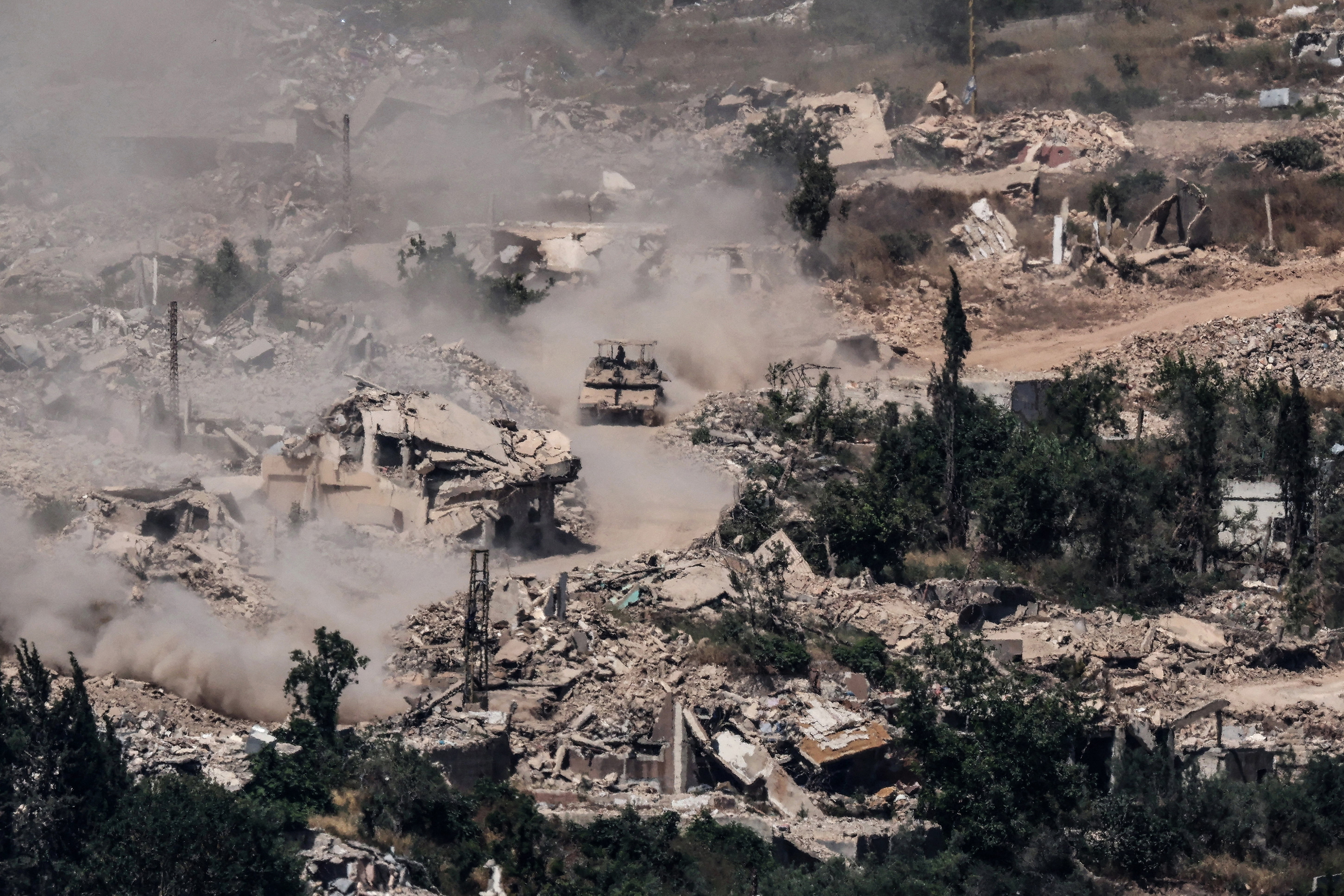 This picture taken from a position in the Upper Galilee in northern Israel, near the Israel-Lebanon border shows Israeli Merkava tanks driving along a road past destroyed buildings in southern Lebanon on June 17, 2026. Lebanon and Israel have been holding direct talks in Washington since April, seeking to end the hostilities between Israel and Hezbollah and separate their conflict from the wider regional war. [Jack Guez/AFP]