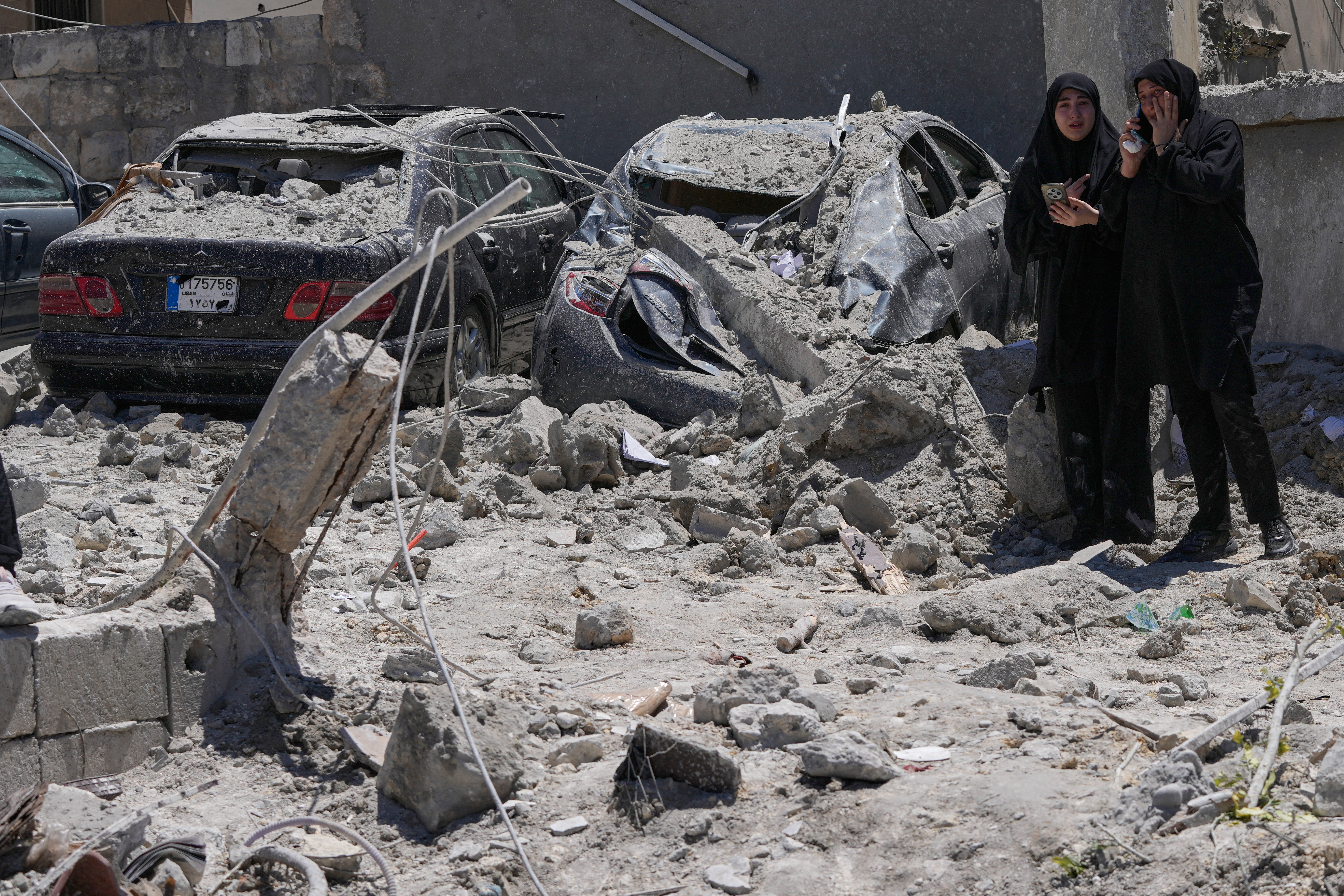 Relatives of missed victims weep, as they gather at the site of destroyed buildings that were hit in an Israeli airstrike in Qannarit village, southern Lebanon