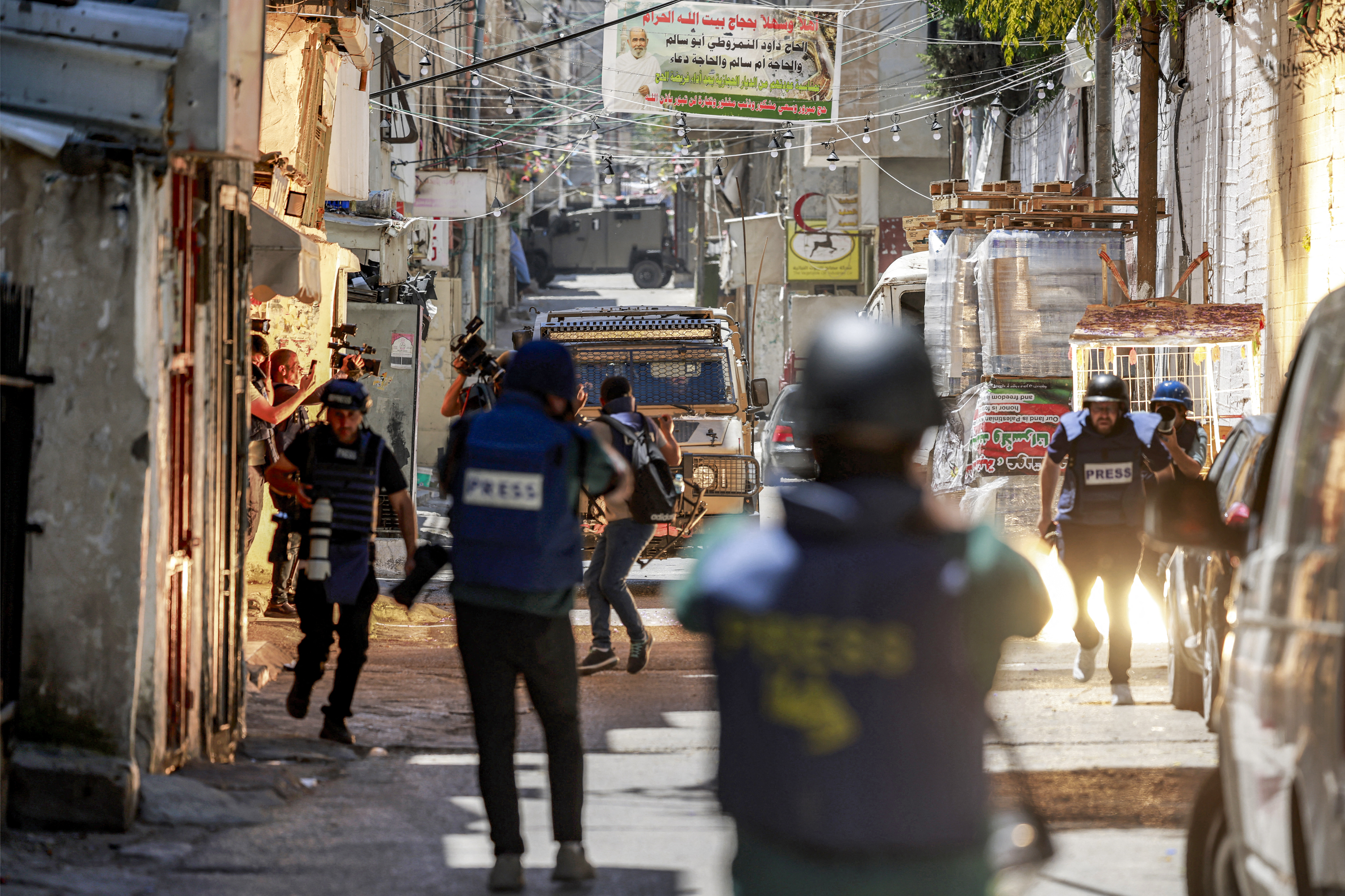 A stun grenade explodes while journalists film as an Israeli army armoured vehicle approaches along an alley in the Balata camp for Palestinian refugees, east of Nablus in the occupied West Bank, during an Israeli military operation on June 7, 2026.