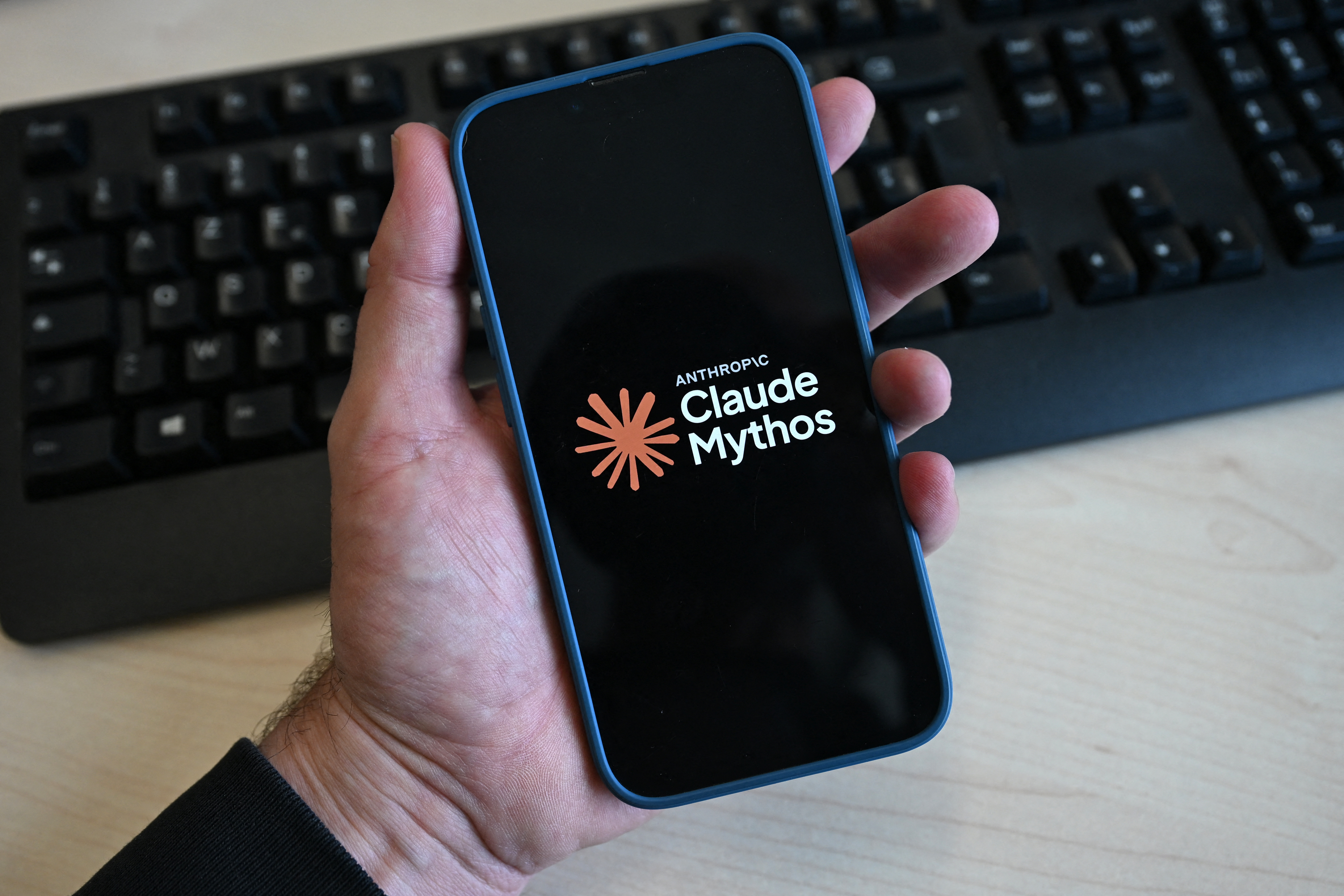 The logo of the AI assistant 'Claude Mythos' is displayed on a mobile phone screen.