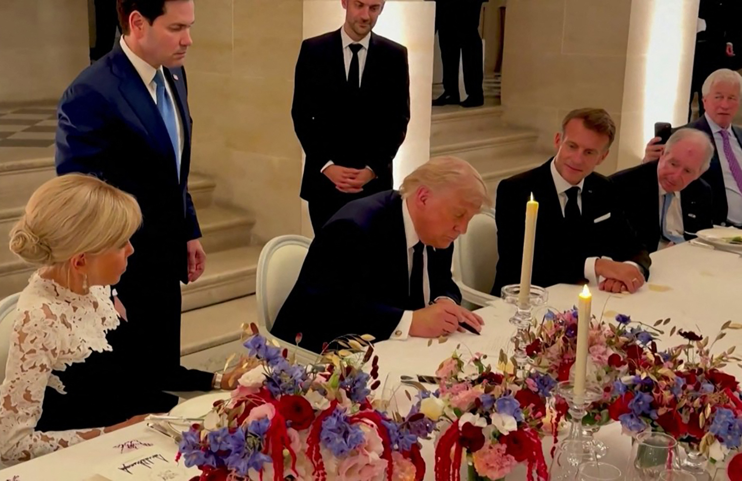TOPSHOT - This screengrab from videofootage made available on June 18, 2026, from the X account of Deputy Chief of Staff at The White House Dan Scavino shows US President Donald Trump (C) next to France's President Emmanuel Macron (R), his wife Brigitte Macron (L), US Secretary of State Marco Rubio and France's Foreign Affairs Minister Jean-Noel Barrot during the signing of a deal with Iran to end the Middle East war, inside Chateau de Versailles, in Versailles southwest of Paris on June 17, 2026. (Photo by @Scavino47 / AFP) / NO USE AFTER JULY 17, 2026 22:00:00 GMT - XGTY - RESTRICTED TO EDITORIAL USE - MANDATORY CREDIT « AFP PHOTO / @SCAVINO47 » - NO MARKETING NO ADVERTISING CAMPAIGNS - DISTRIBUTED AS A SERVICE TO CLIENTS - NO ARCHIVE