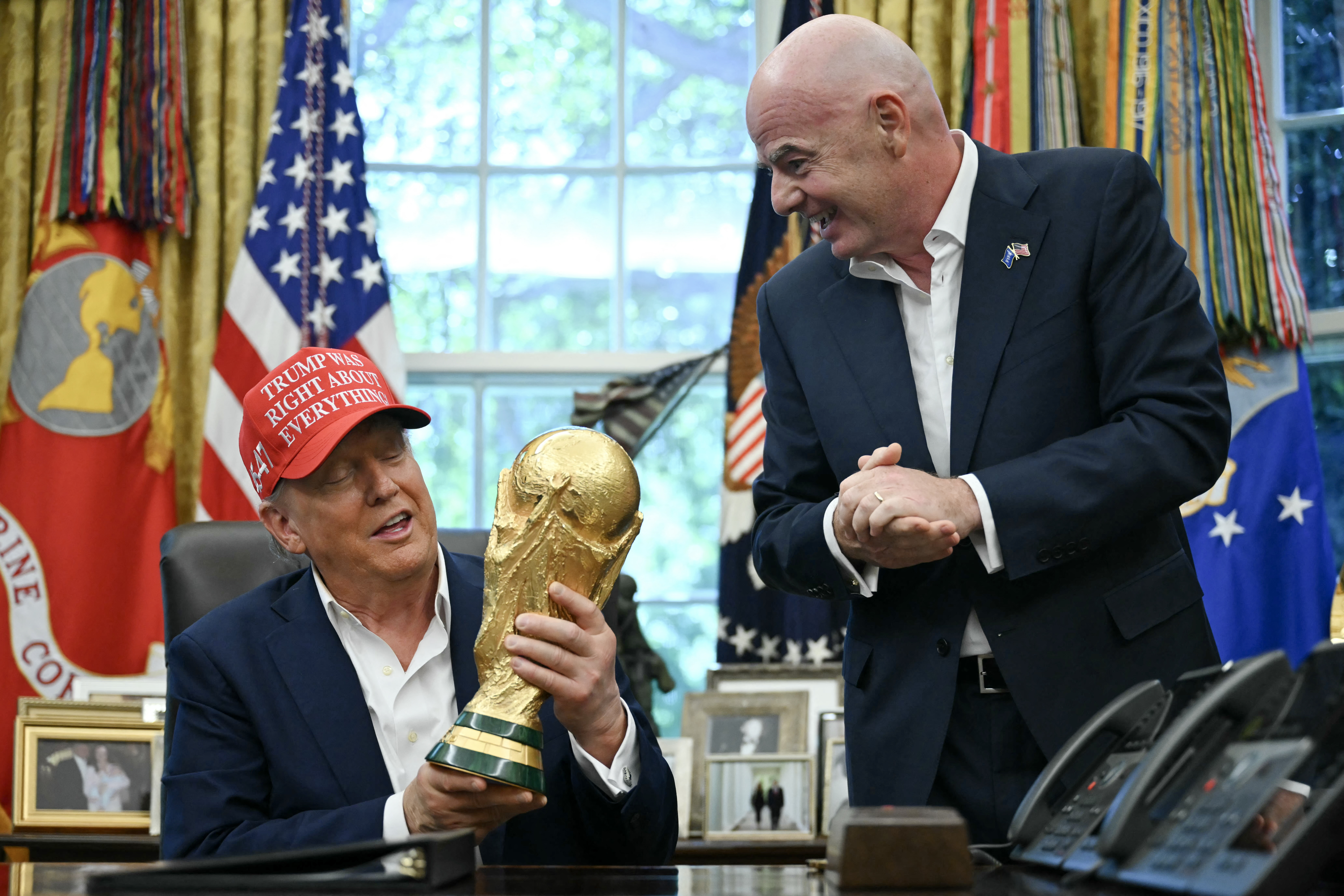 (FILES) US President Donald Trump joined by FIFA president Gianni Infantino (R) holds the World Cup Trophy as he makes an announcement in the Oval Office of the White House in Washington, DC, on August 22, 2025.