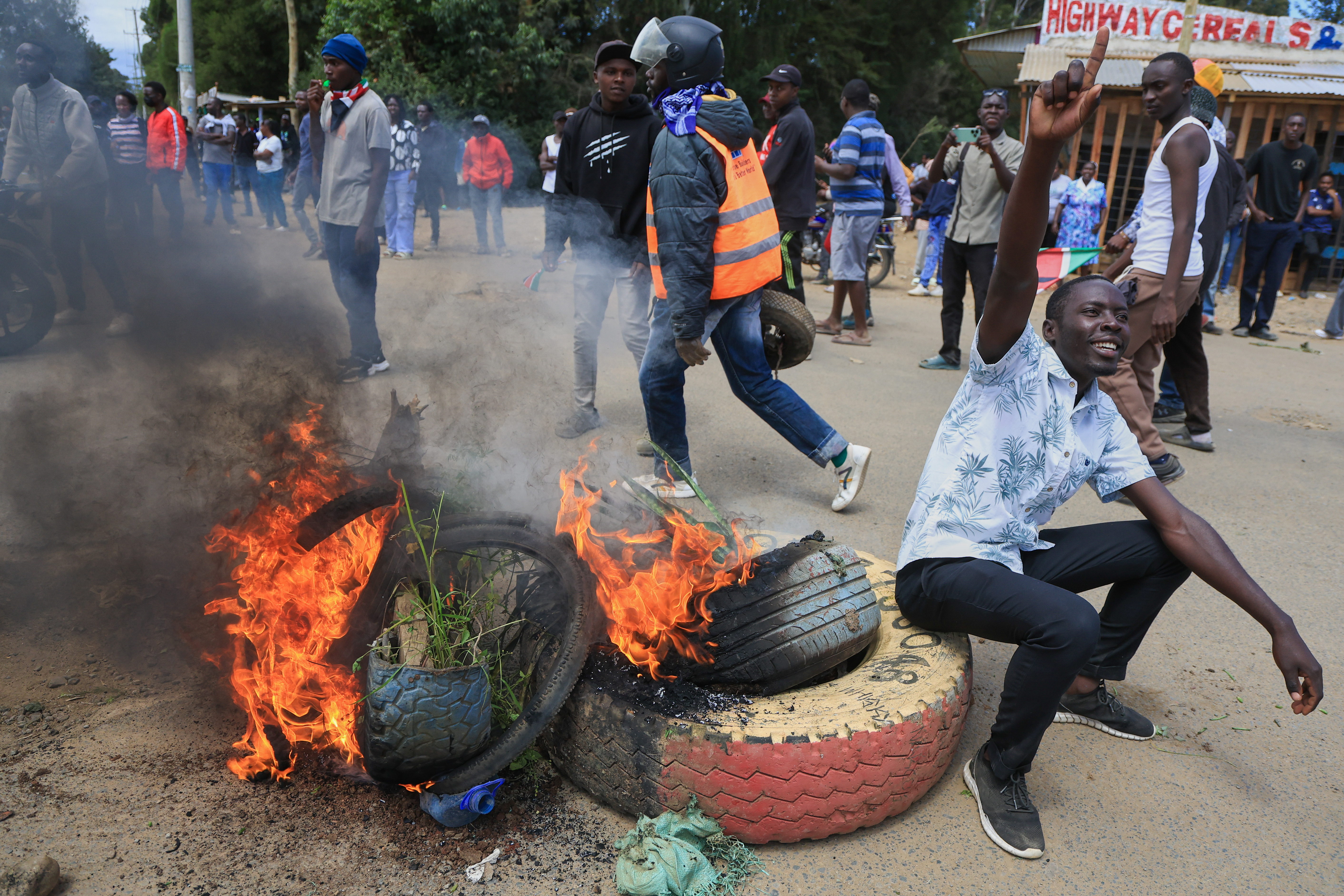 A protester gestures beside a burning barricade during a demonstration against a proposed Ebola quarantine center to be established by the United States at Laikipia Air Base in Nanyuki, Kenya, Monday, June 1, 2026. (AP Photo/Andrew Kasuku)