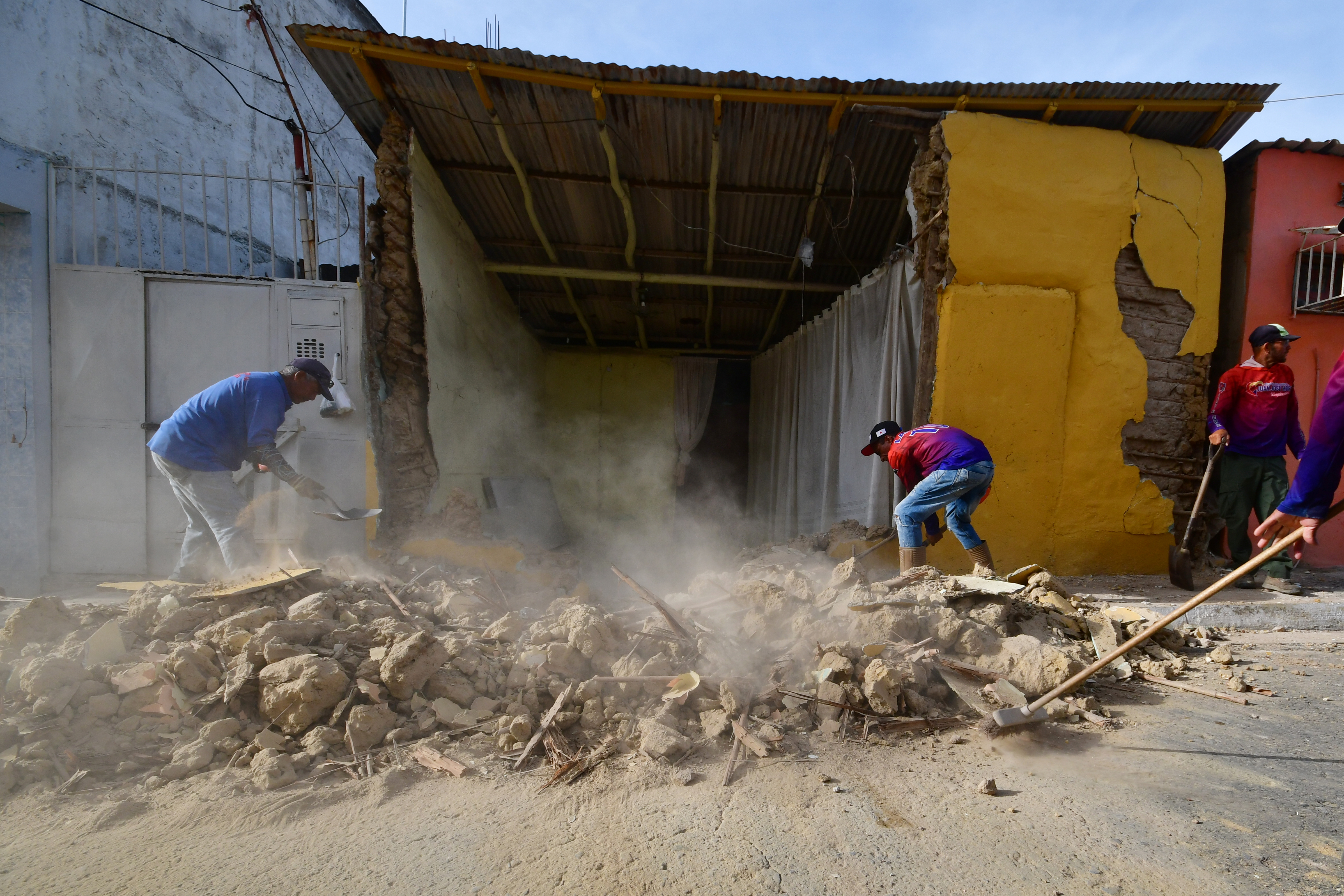 Residents clean up rubble in Moron, near the epicenter of two earthquakes that struck Venezuela a day earlier, Thursday, June 25, 2026. (AP Photo/Jacinto Oliveros)