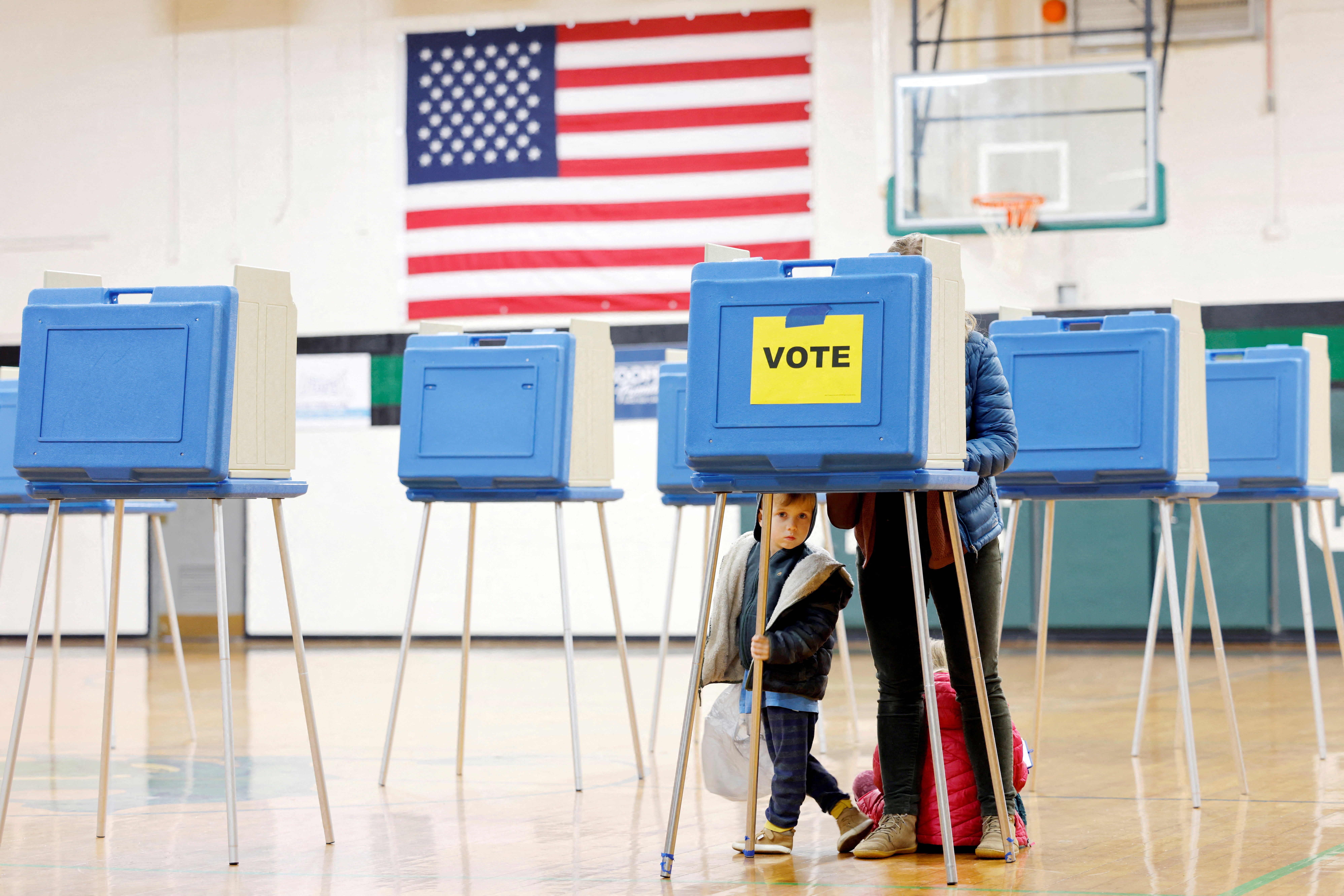 FILE PHOTO: A boy peers out from under a voting booth as his mother marks her ballot during the state?s primary election to choose candidates for the November midterm elections, in Cary, North Carolina, U.S., March 3, 2026. REUTERS/Jonathan Drake/File Photo