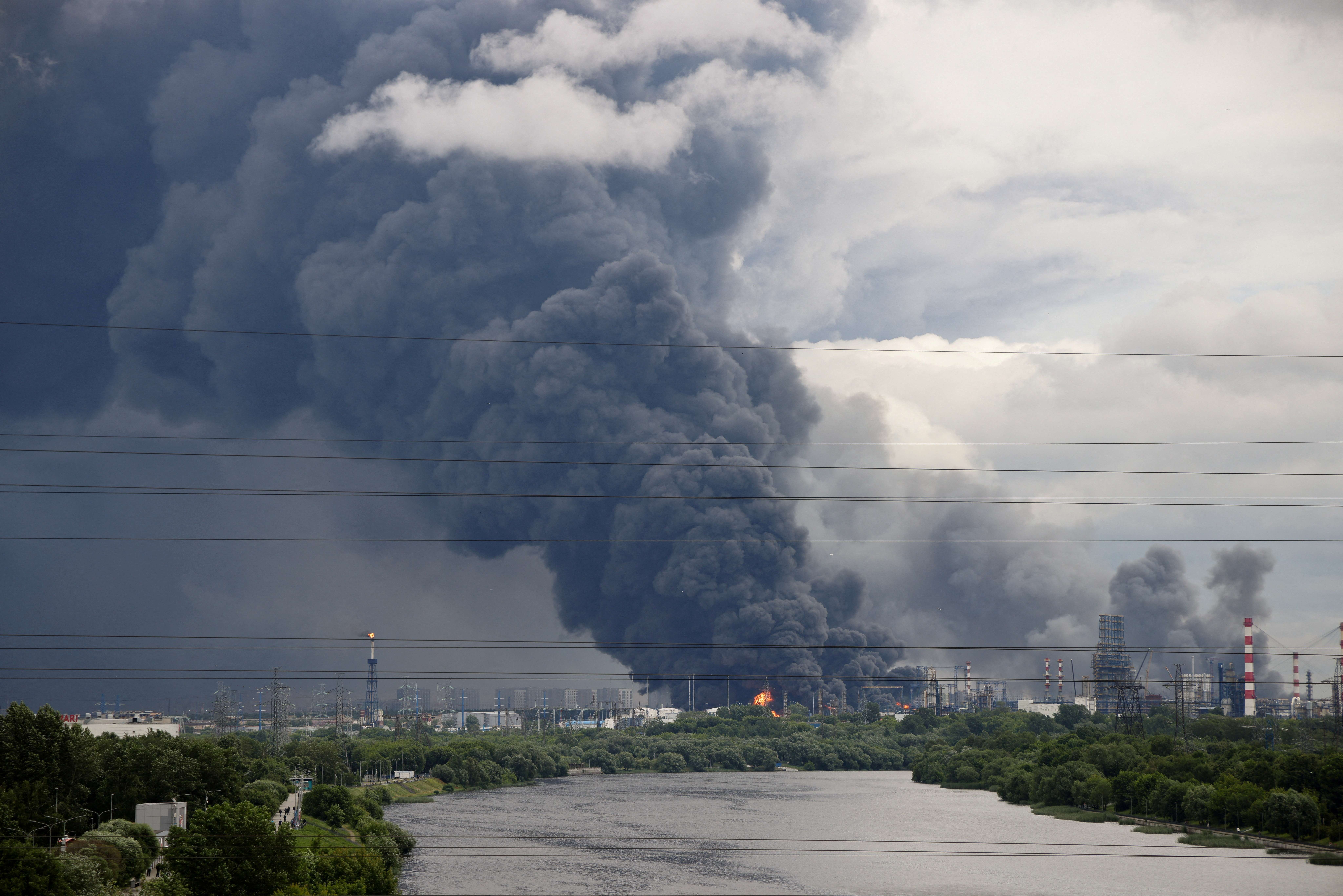 Thick plumes of smoke with flames rise from an oil refinery following a Ukrainian drone attack