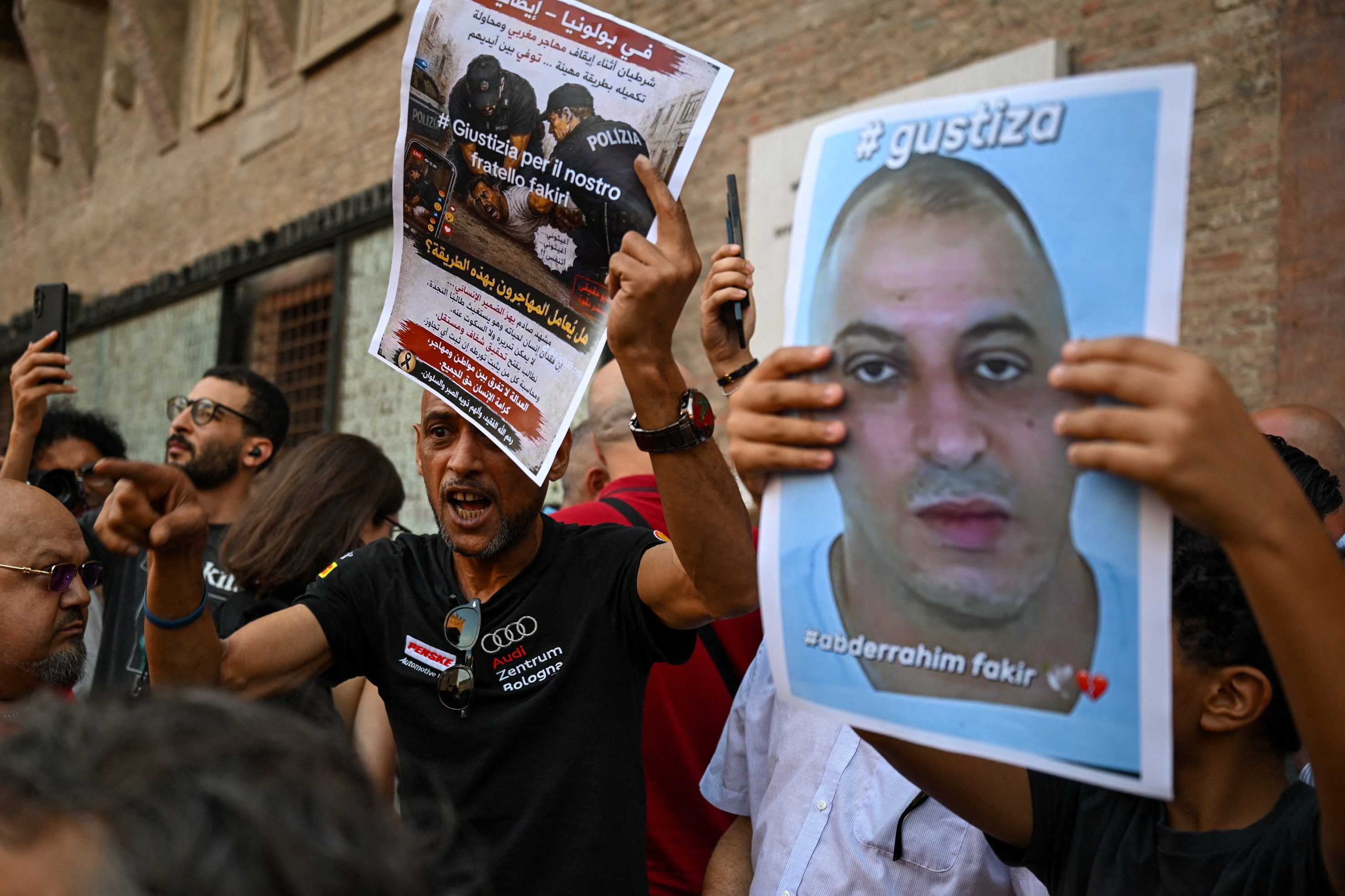 A protester gestures while holding a flyer during a protest following the death of Abderrahim Fakir in Bologna