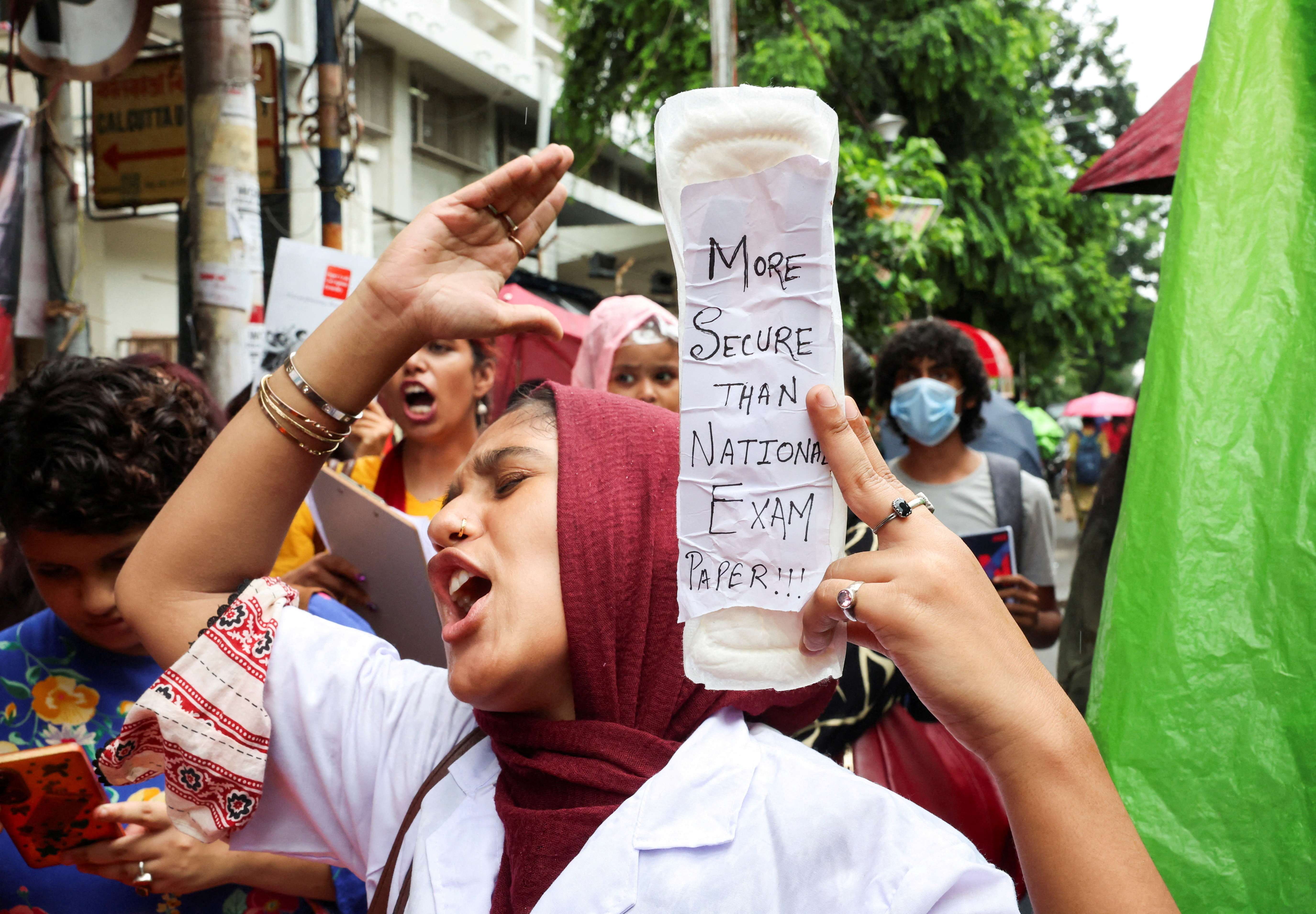 A woman holds a sanitary pad with a slogan in solidarity with India’s Cockroach Janta Party protests held at Jantar Mantar in New Delhi, which demand the resignation of Education Minister Dharmendra Pradhan over exam paper leaks, in Kolkata, India, on July 22, 2026