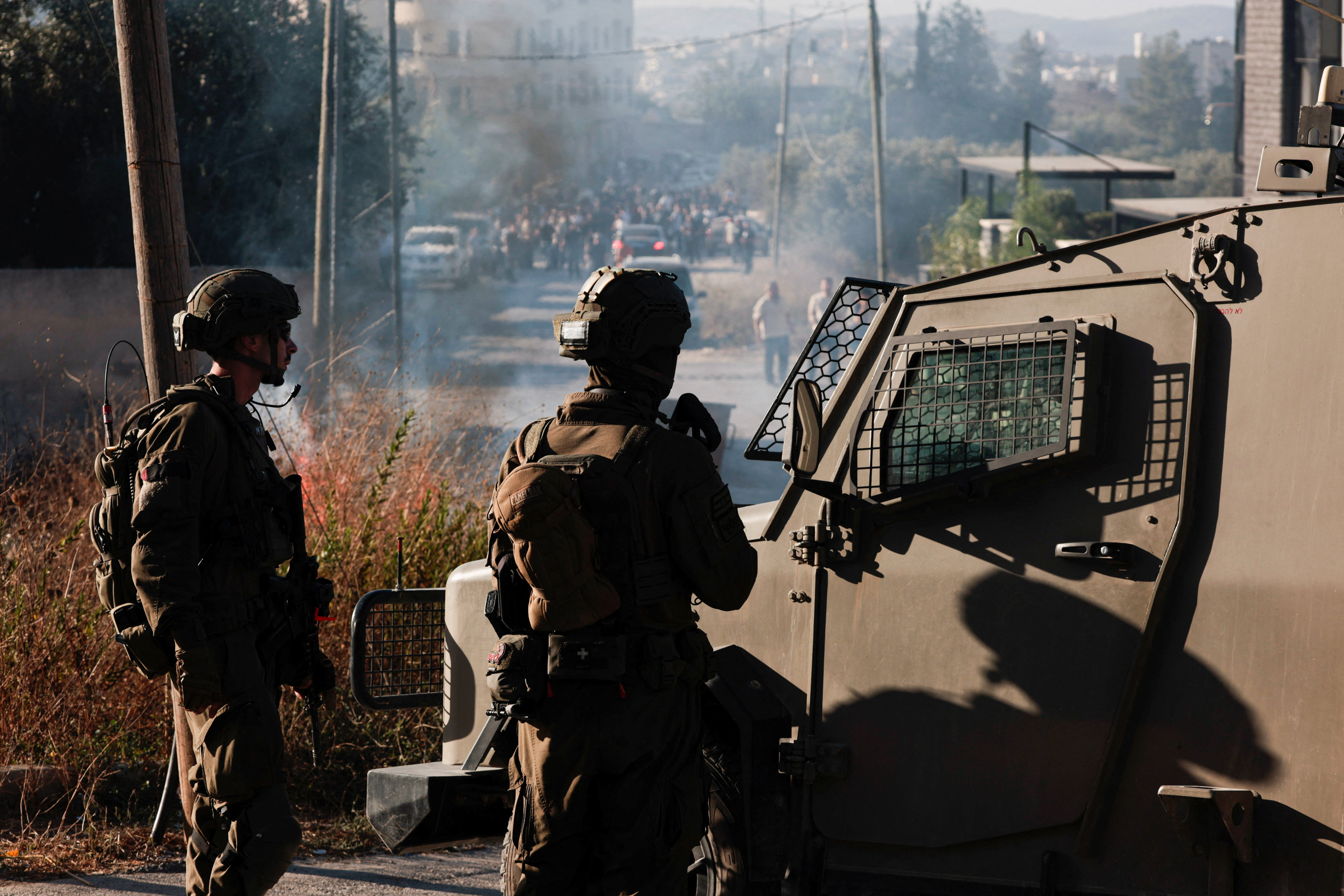 Members of the Israeli military in front of Palestinians gathered following an attack by Israeli settlers, in Serra near Nablus, in the Israeli-occupied West Bank, July 24, 2026. [Mohammed Torokman/Reuters]