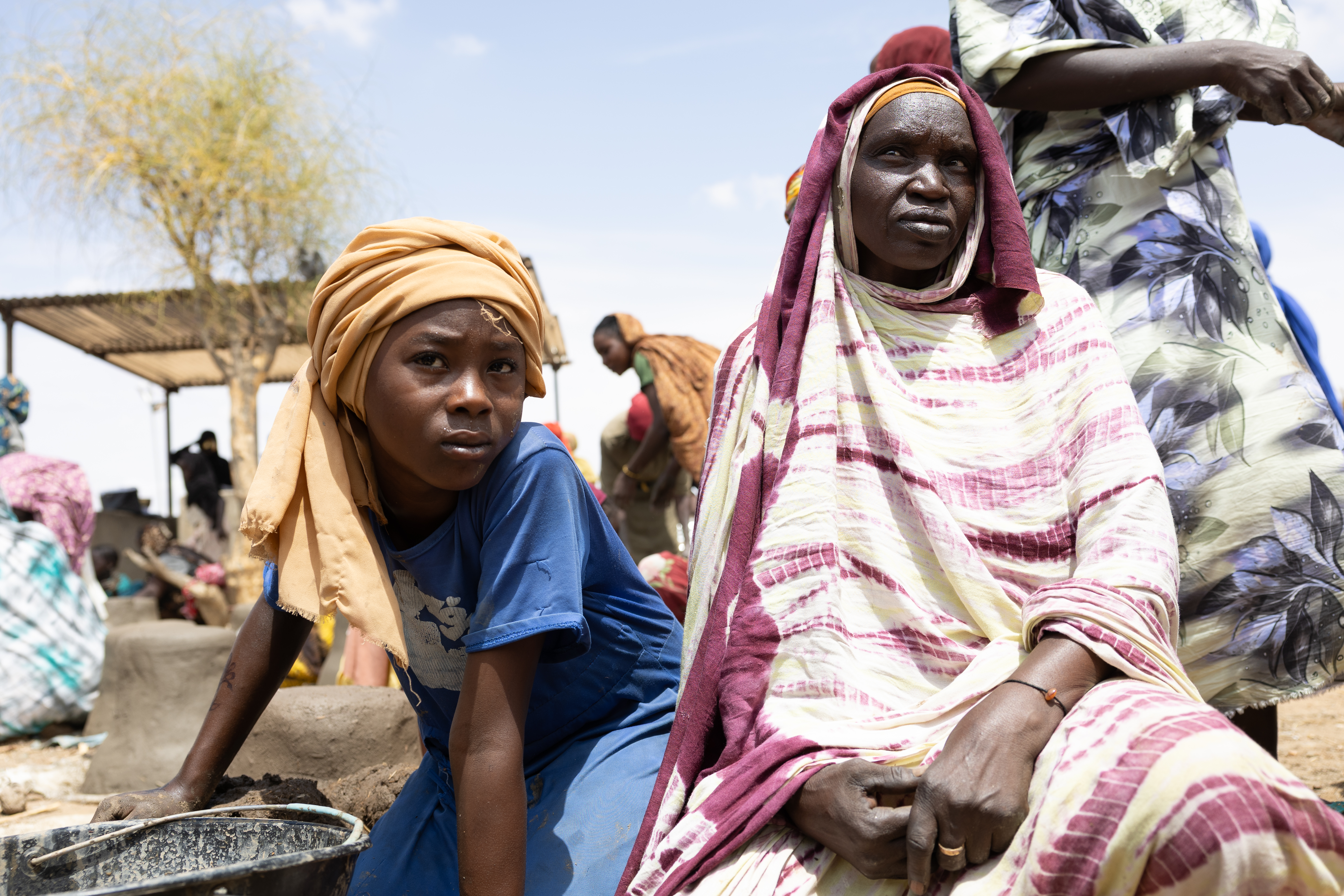 Fatne Adam (right), who fled Sudan in 2023, has lived in Metche refugee camp in eastern Chad ever since. She says her husband and son were shot by snipers as the family escaped the war.